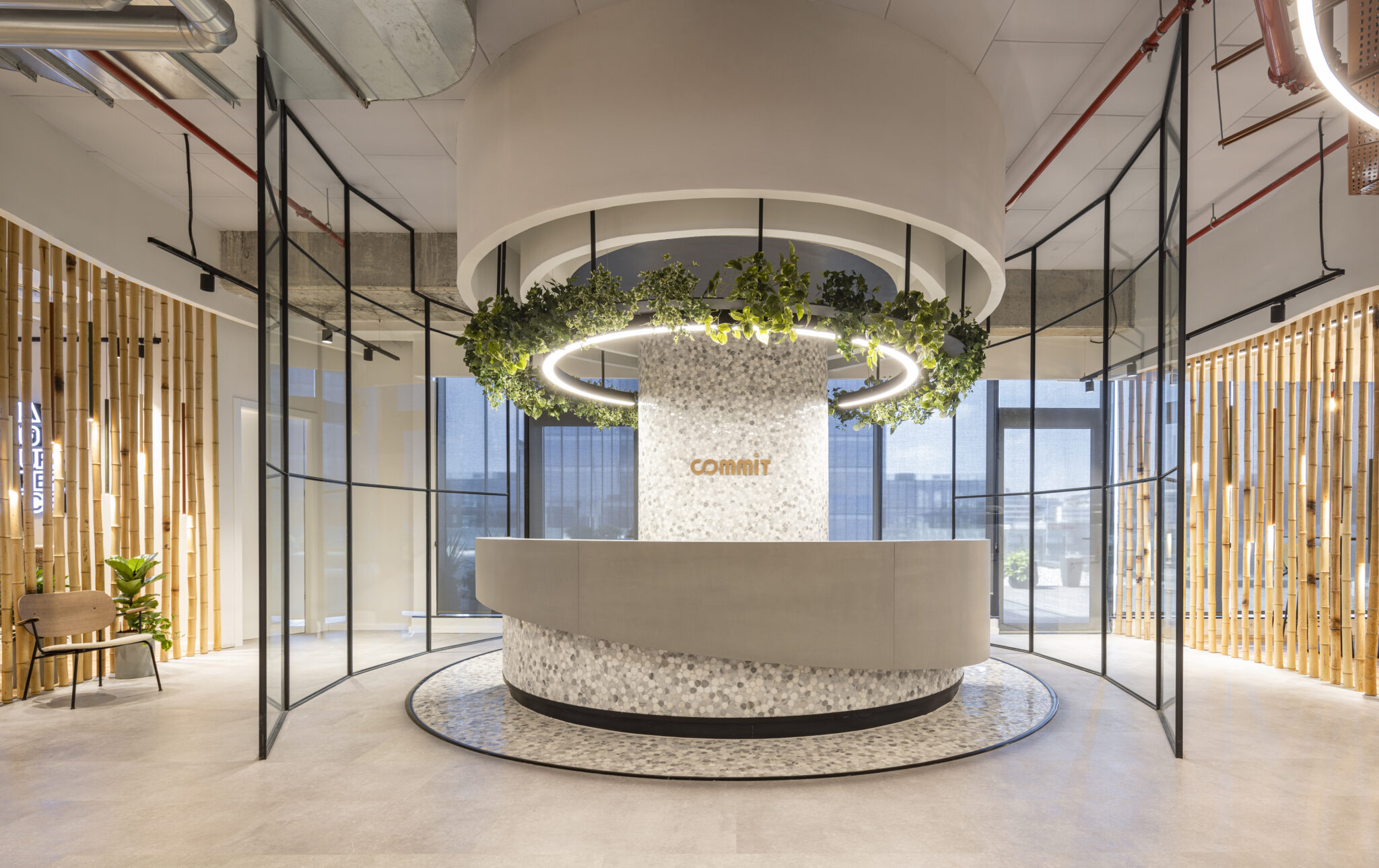 Round terrazzo reception desk under a planted ring light