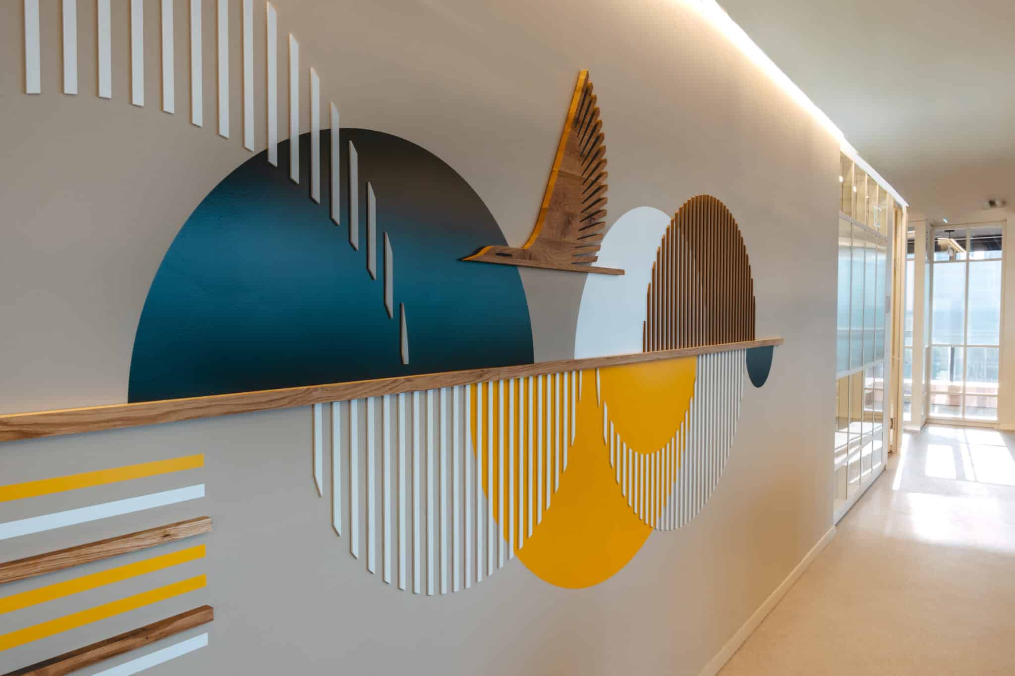 Wall graphic with a wood bird sculpture and coloured arcs