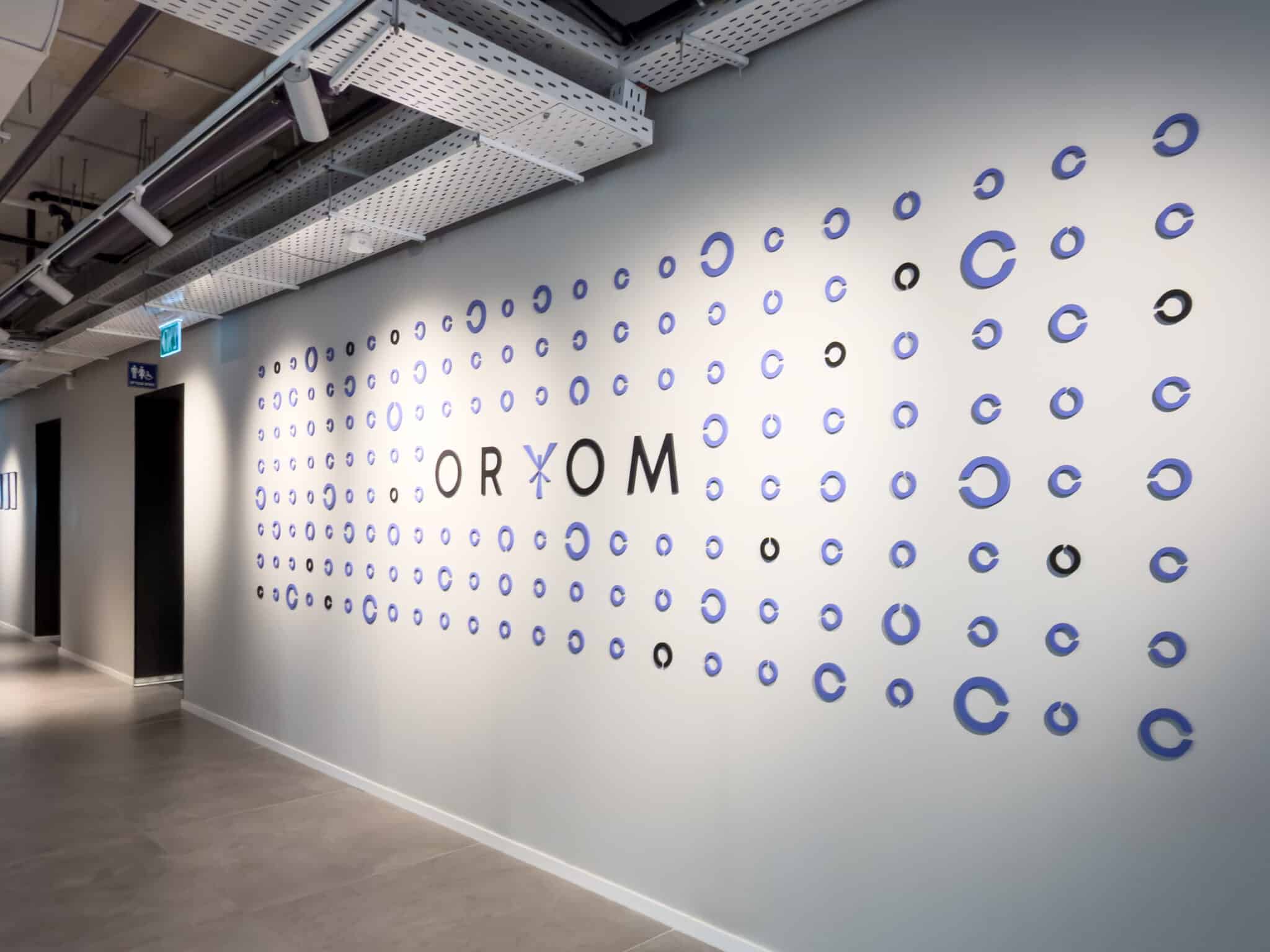 ORYOM 3D lettering on a wall of blue circle elements