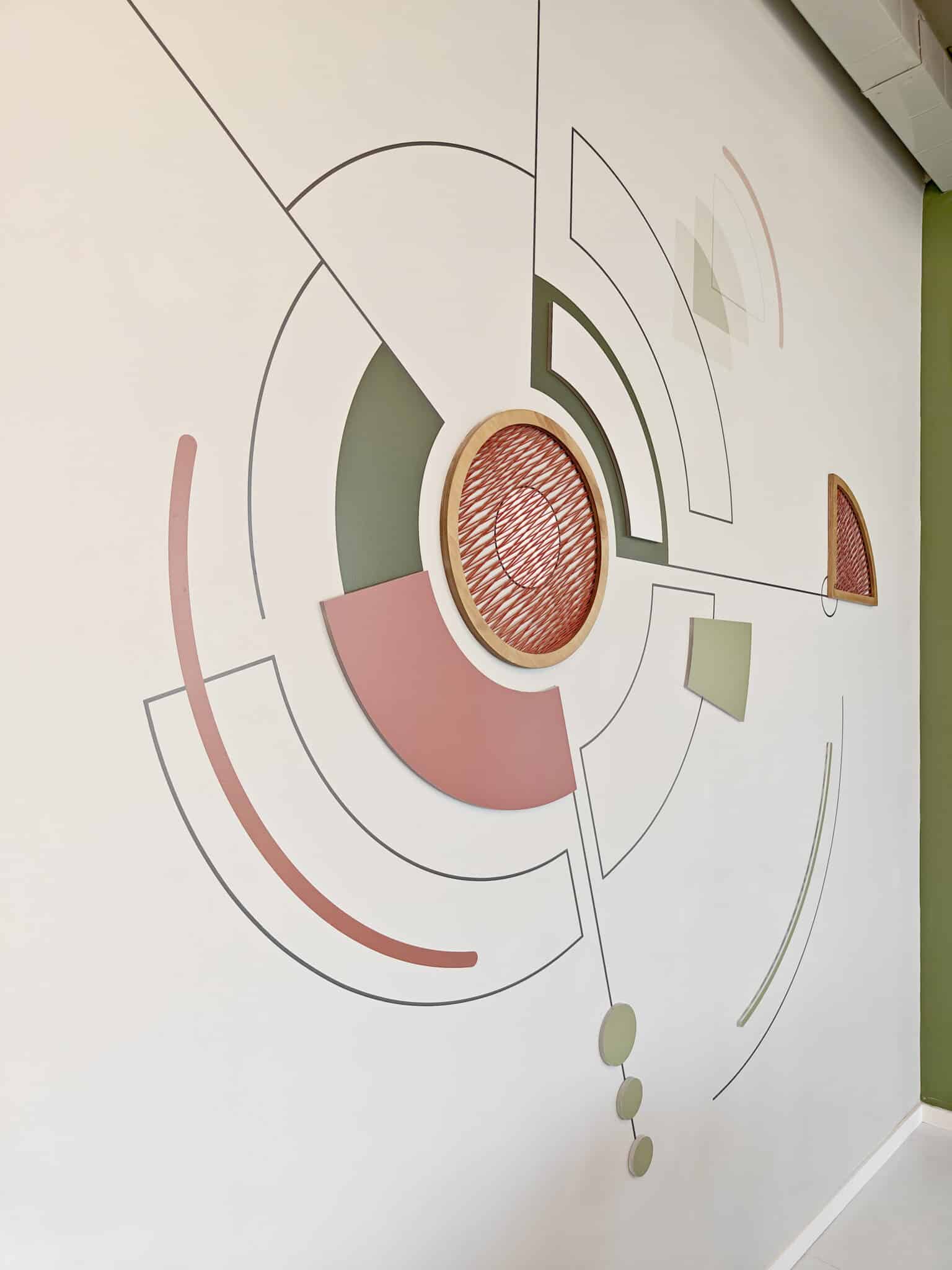 Circular wall graphic with a raised woven disc in green and coral