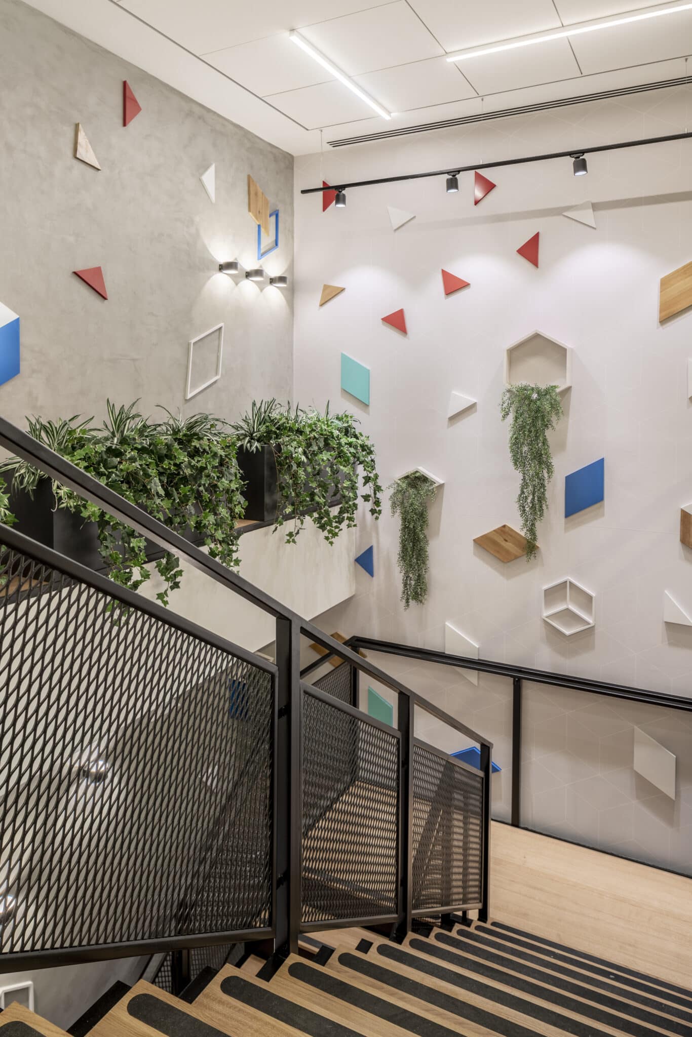 Coloured geometric shapes and planters on a stairwell wall