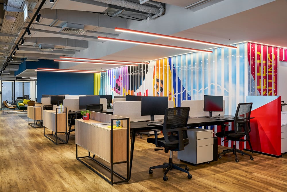 Colourful striped wall graphic with neon lettering behind office desks