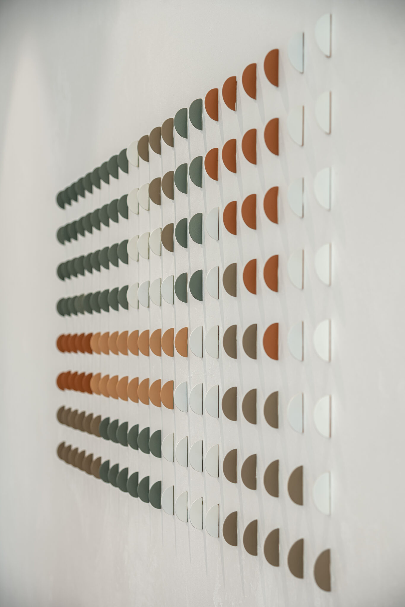 Grid of coloured half circle 3D elements on a white wall