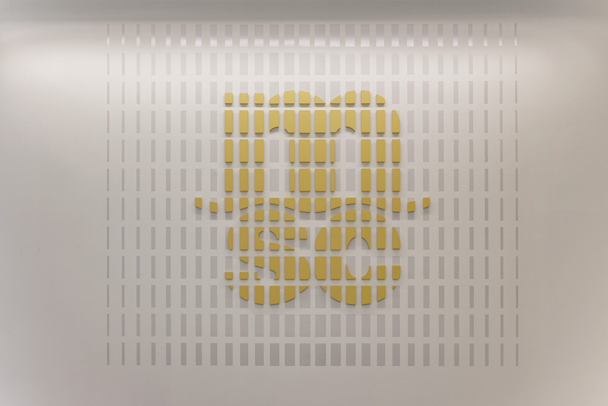 Logo built from short yellow and white 3D bars on a wall