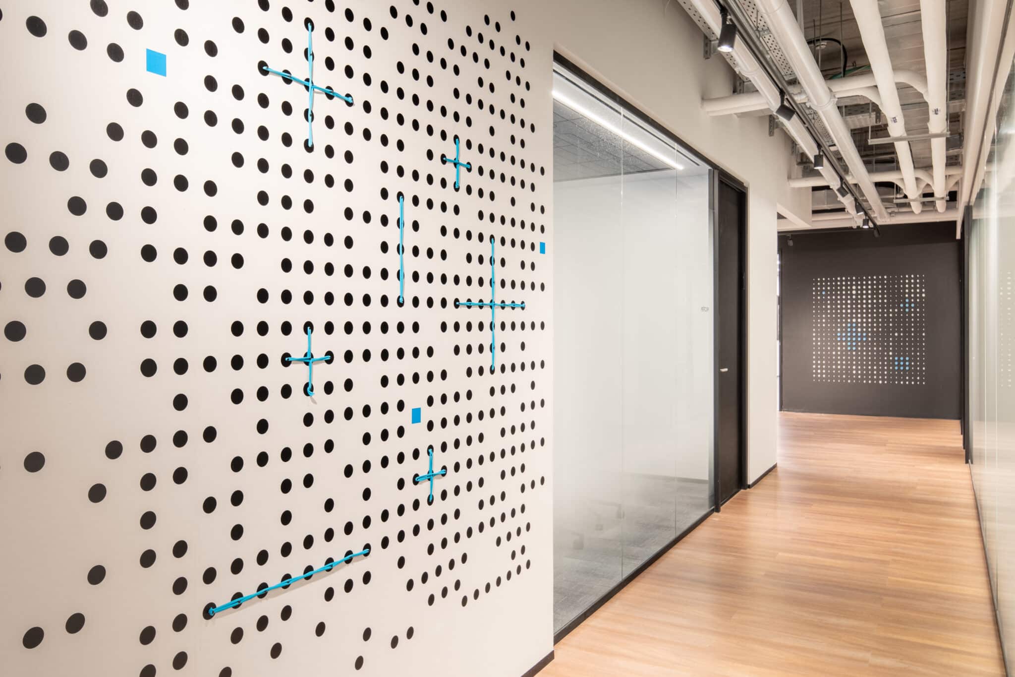 Black dot pattern wall graphic with blue crosses along a corridor