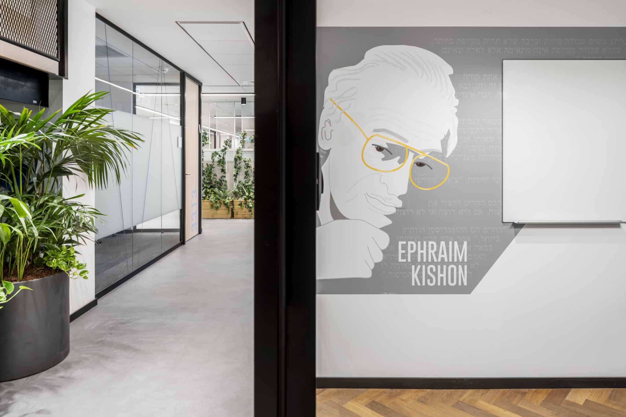 EPHRAIM KISHON portrait wall graphic beside a whiteboard