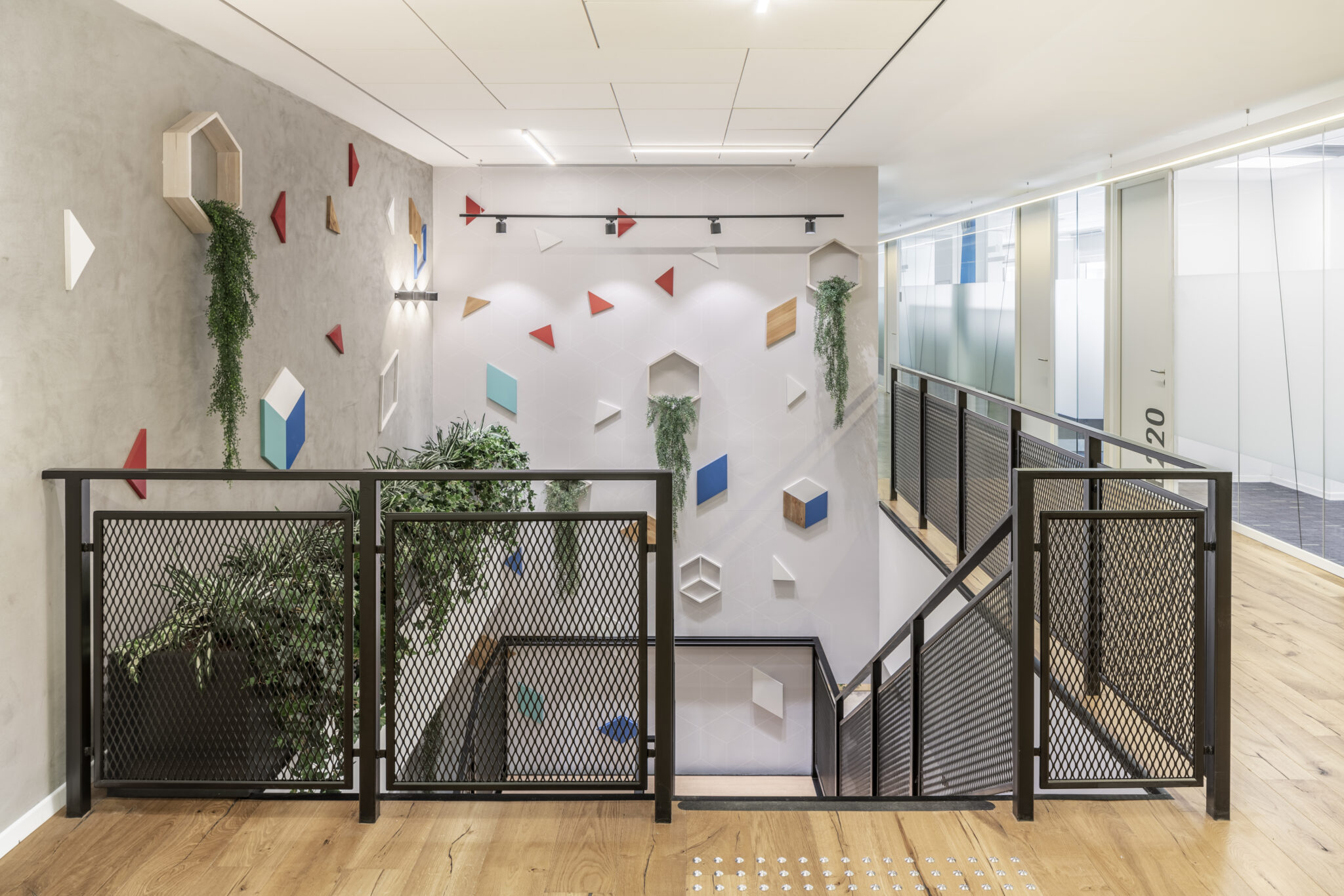 Scattered 3D geometric shapes and planters on a stairwell wall