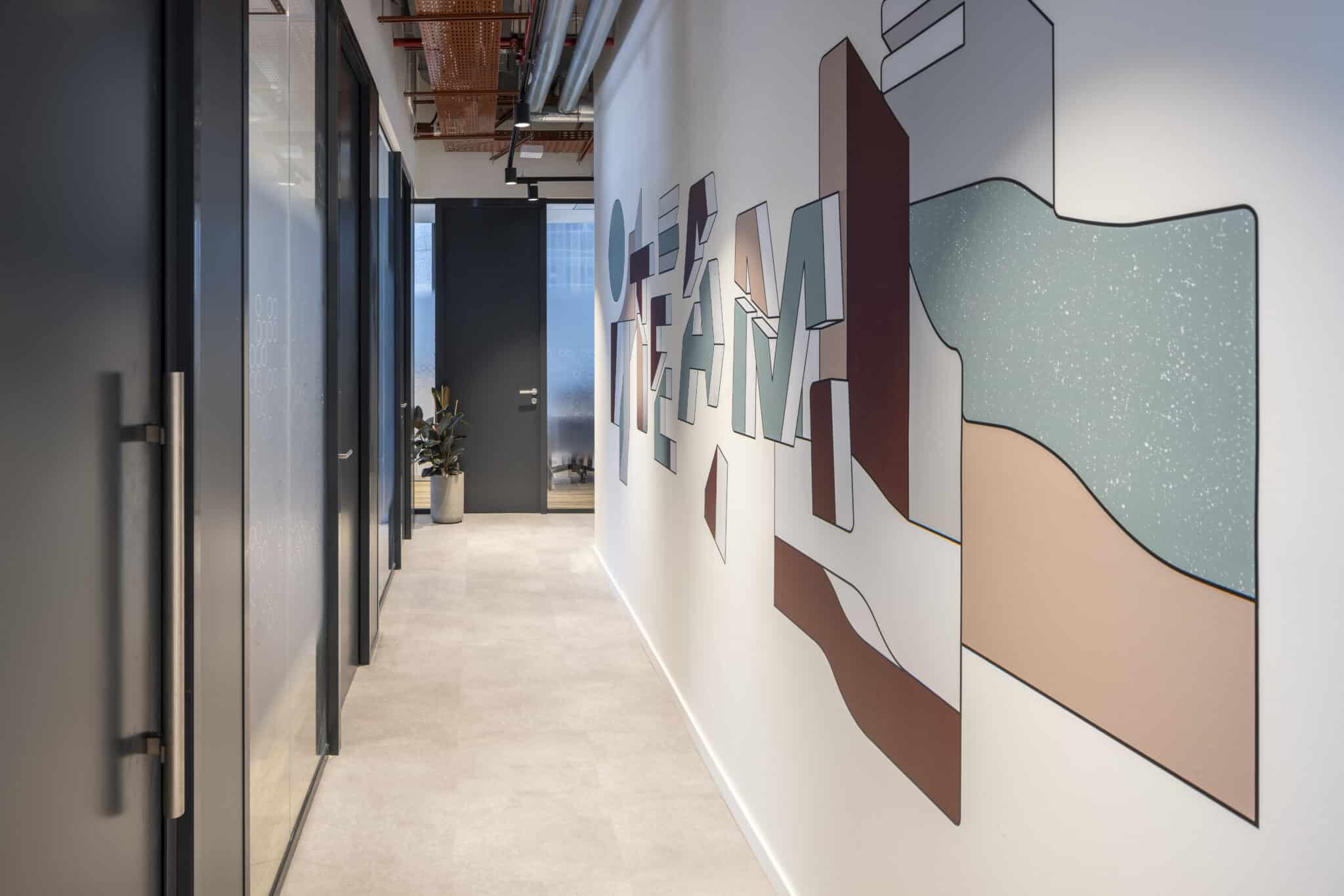 TEAM 3D letters on a layered colour wall panel in a corridor
