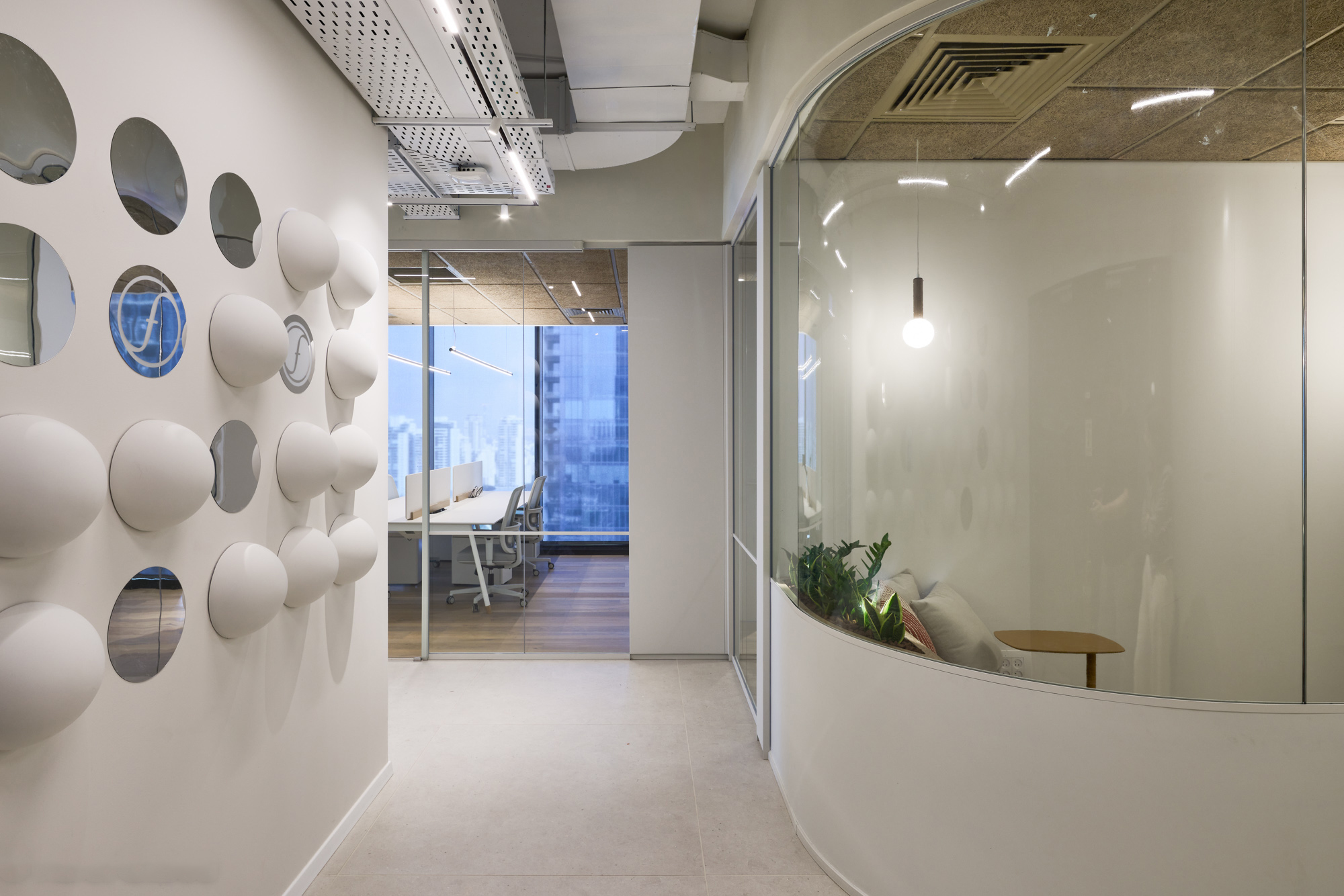 White 3D domes and discs on a wall beside curved frosted glass