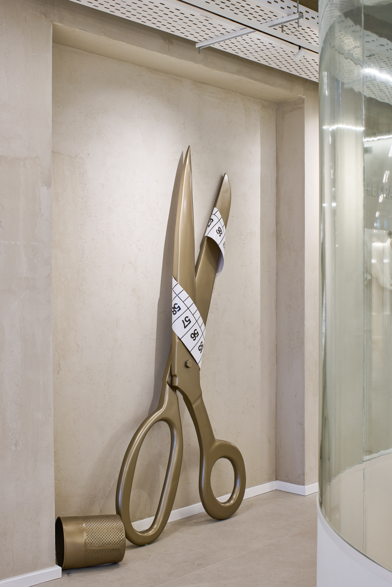 Oversized gold scissors sculpture with a tape measure in a niche