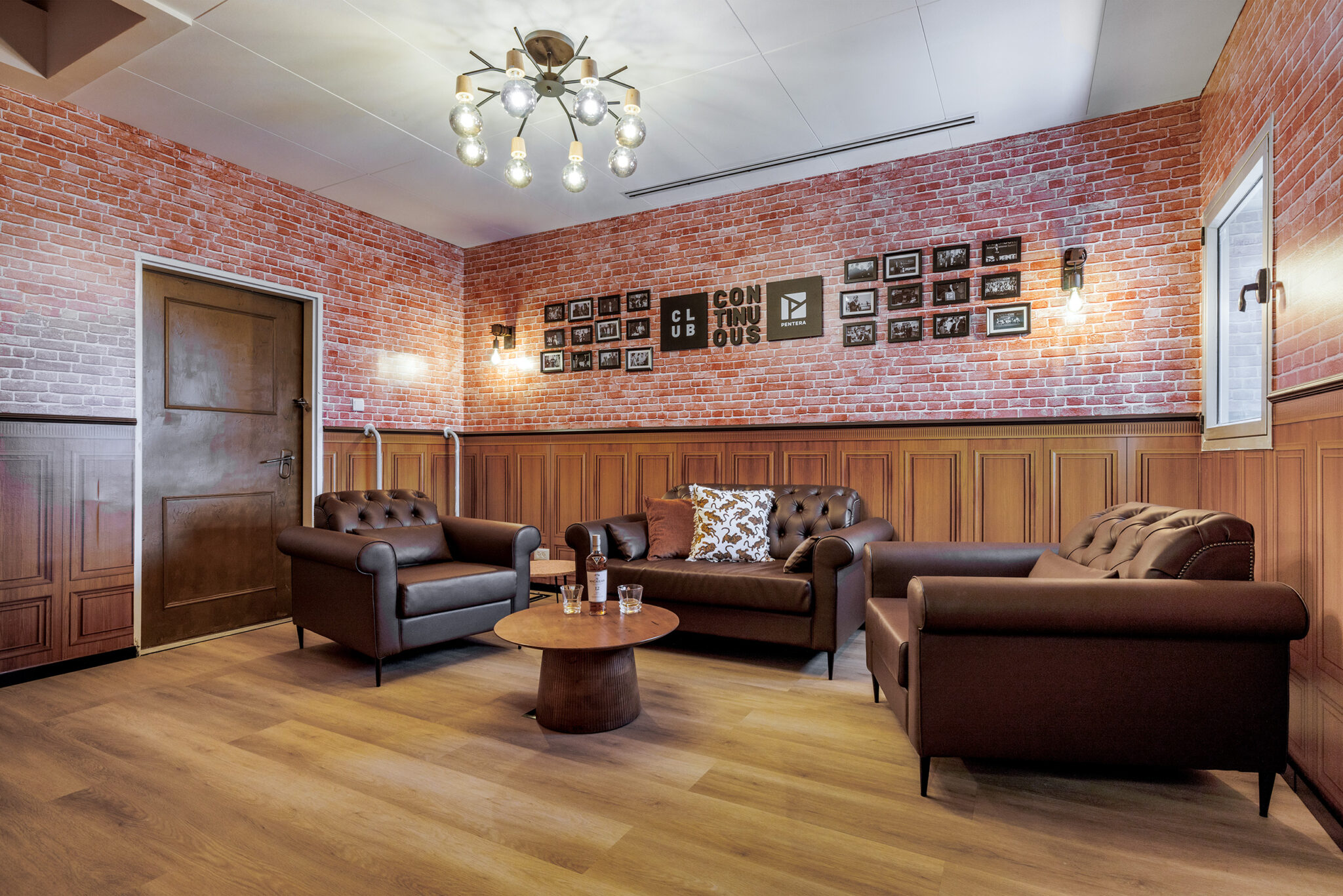 Framed photos and a CLUB CONTINUOUS sign on a brick wall