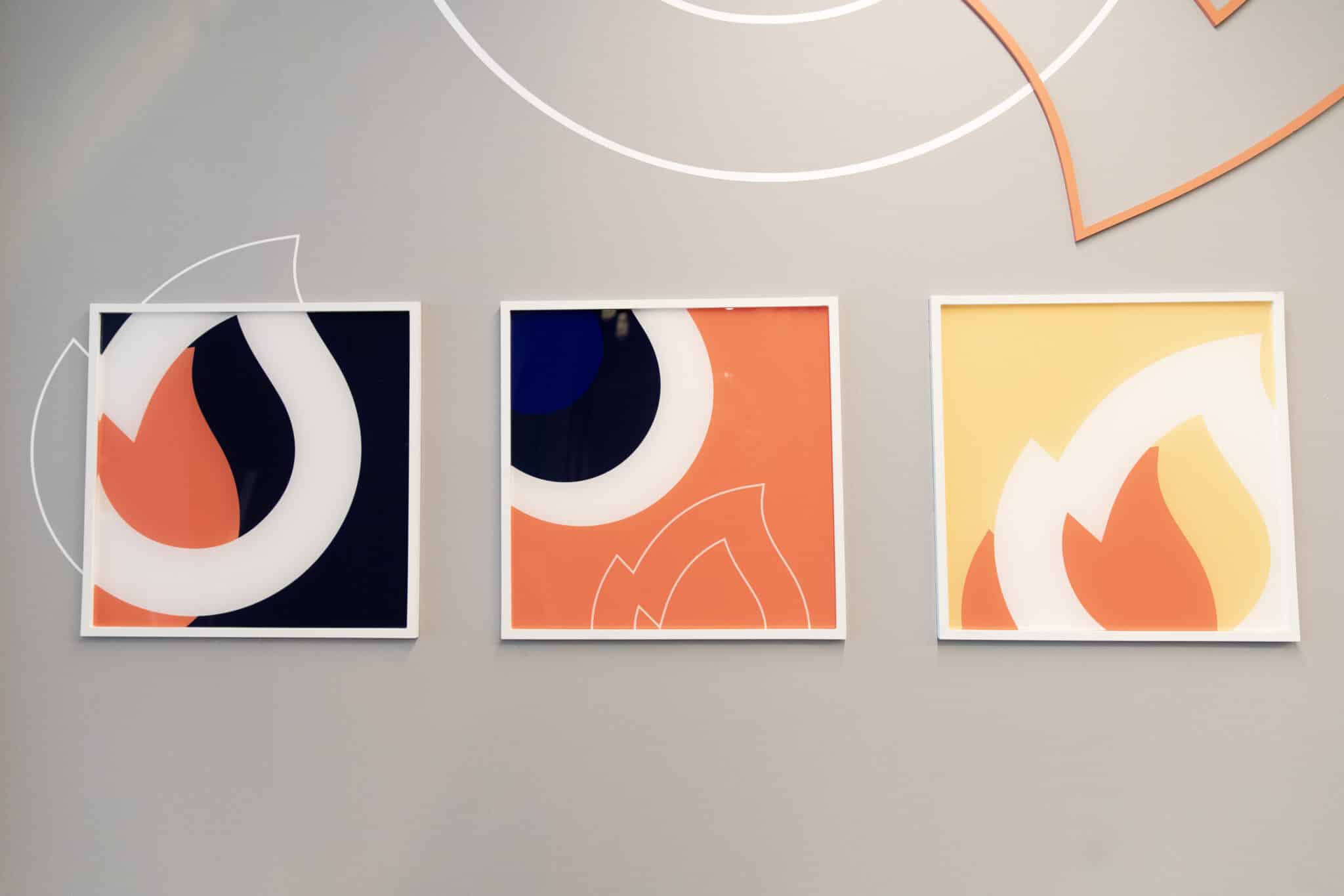 Three framed flame graphics in orange and navy on a wall