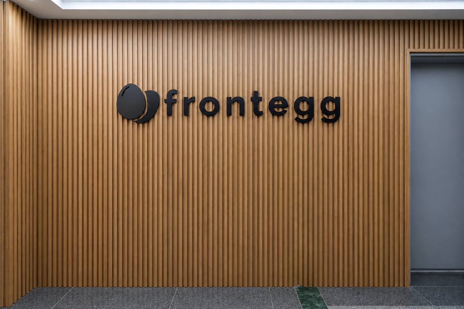 frontegg 3D logo on a wood slat reception wall