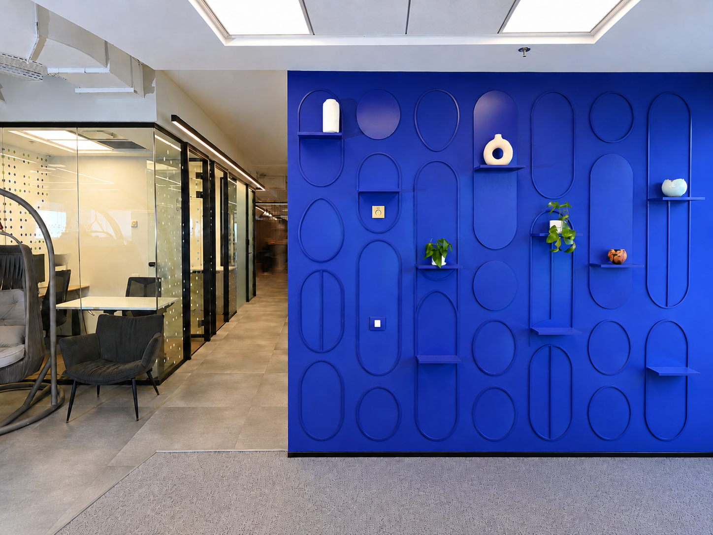 Blue arch relief cladding wall with shelves beside dot pattern glass