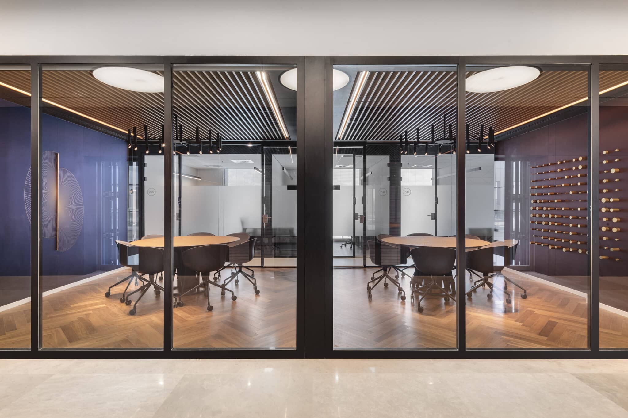Two meeting rooms behind glass with wall graphics in blue and burgundy