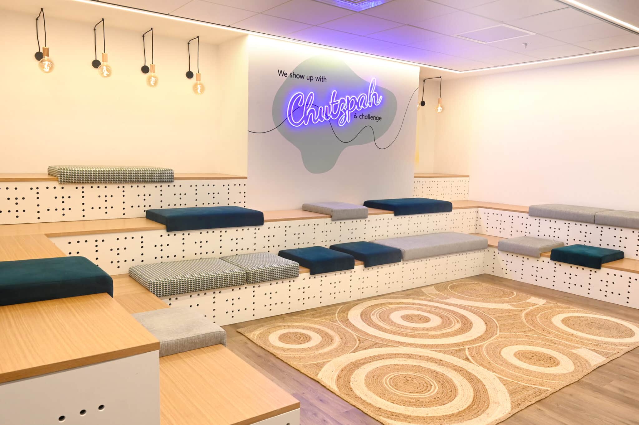Backlit Chutzpah neon sign on a wall above tiered seating