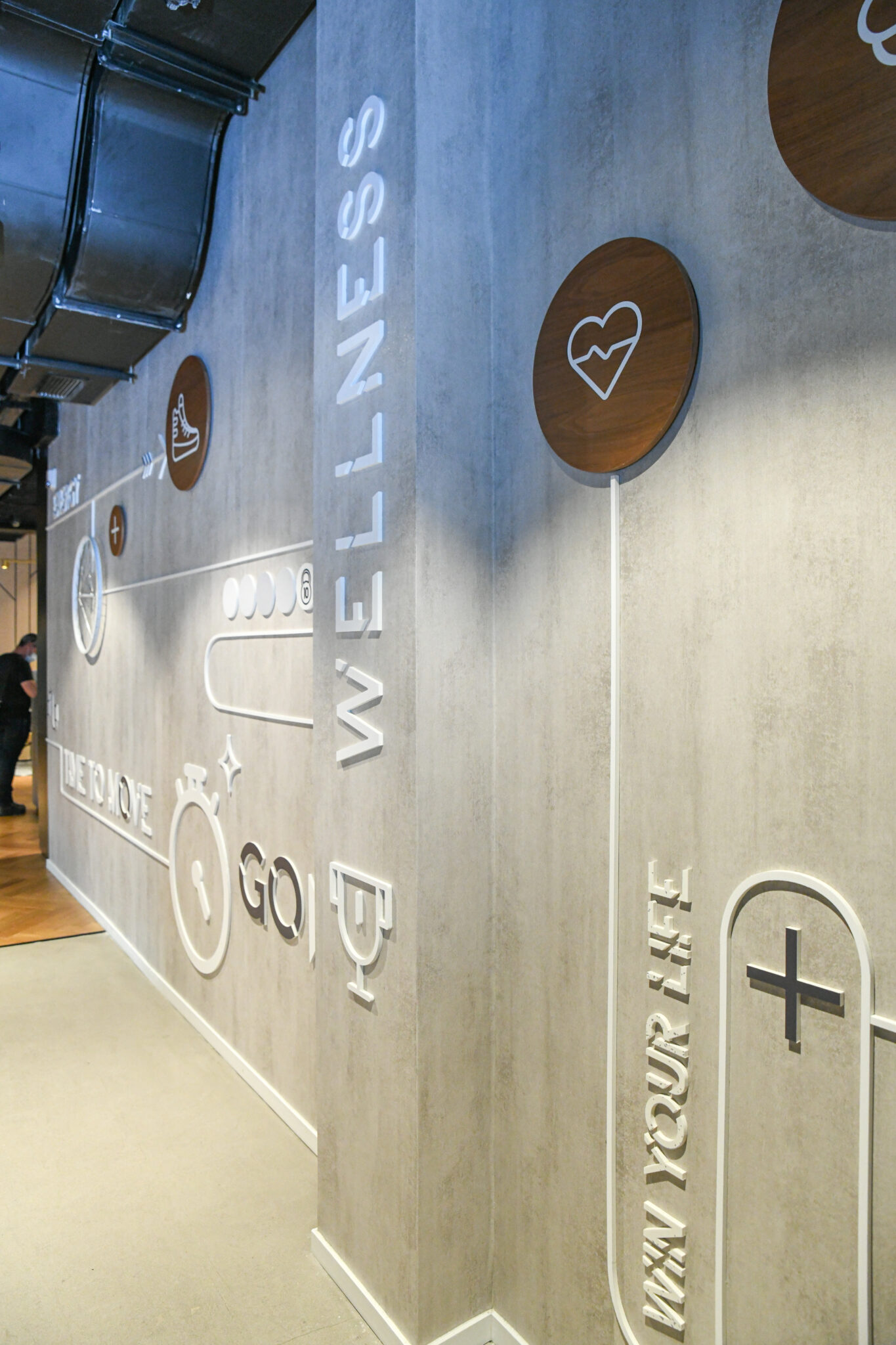 WELLNESS 3D letters with wood icon discs on a concrete wall