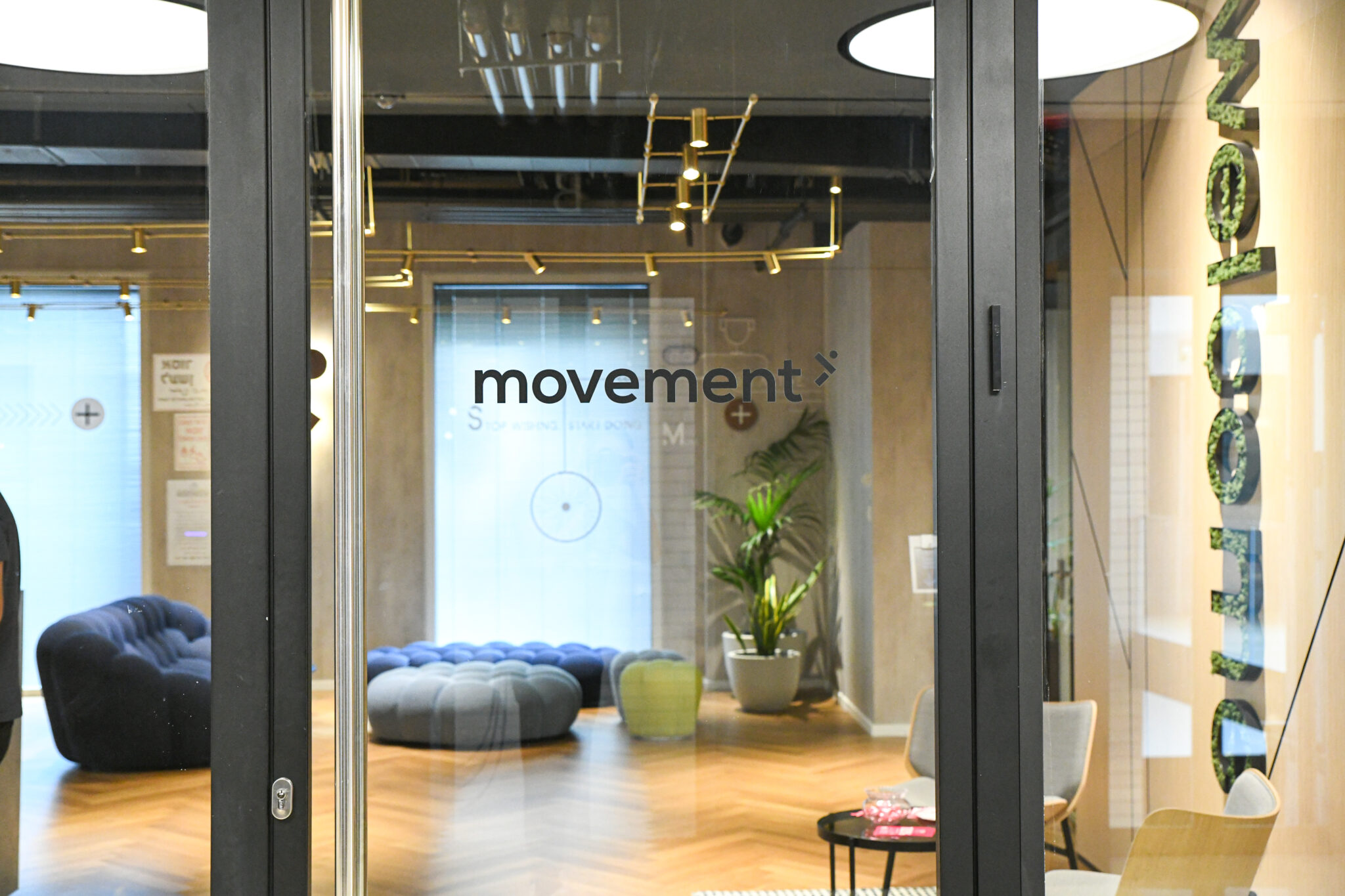 movement logo on entrance glass beside vertical moss letters