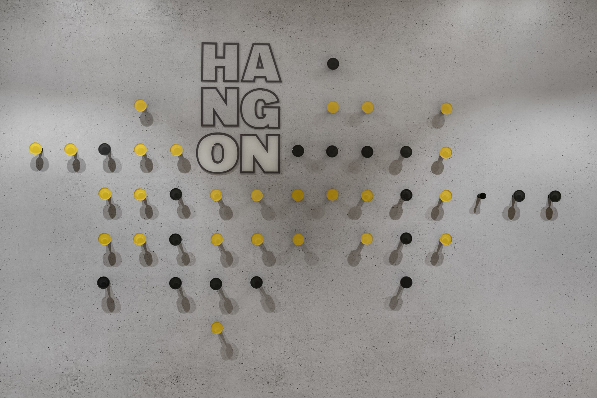 HANG ON 3D letters with yellow and black hooks on concrete