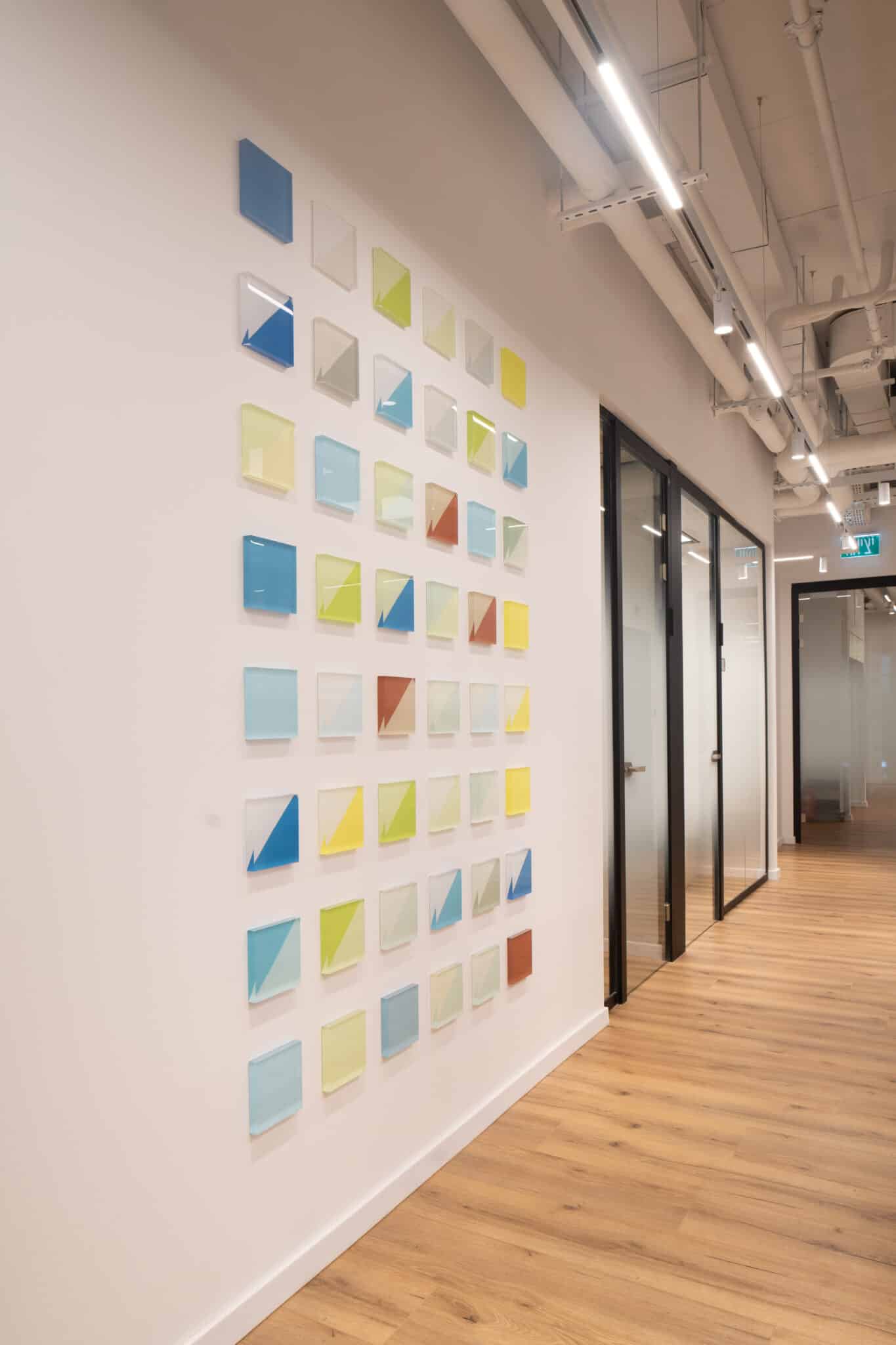 Grid of coloured square tiles along a corridor wall