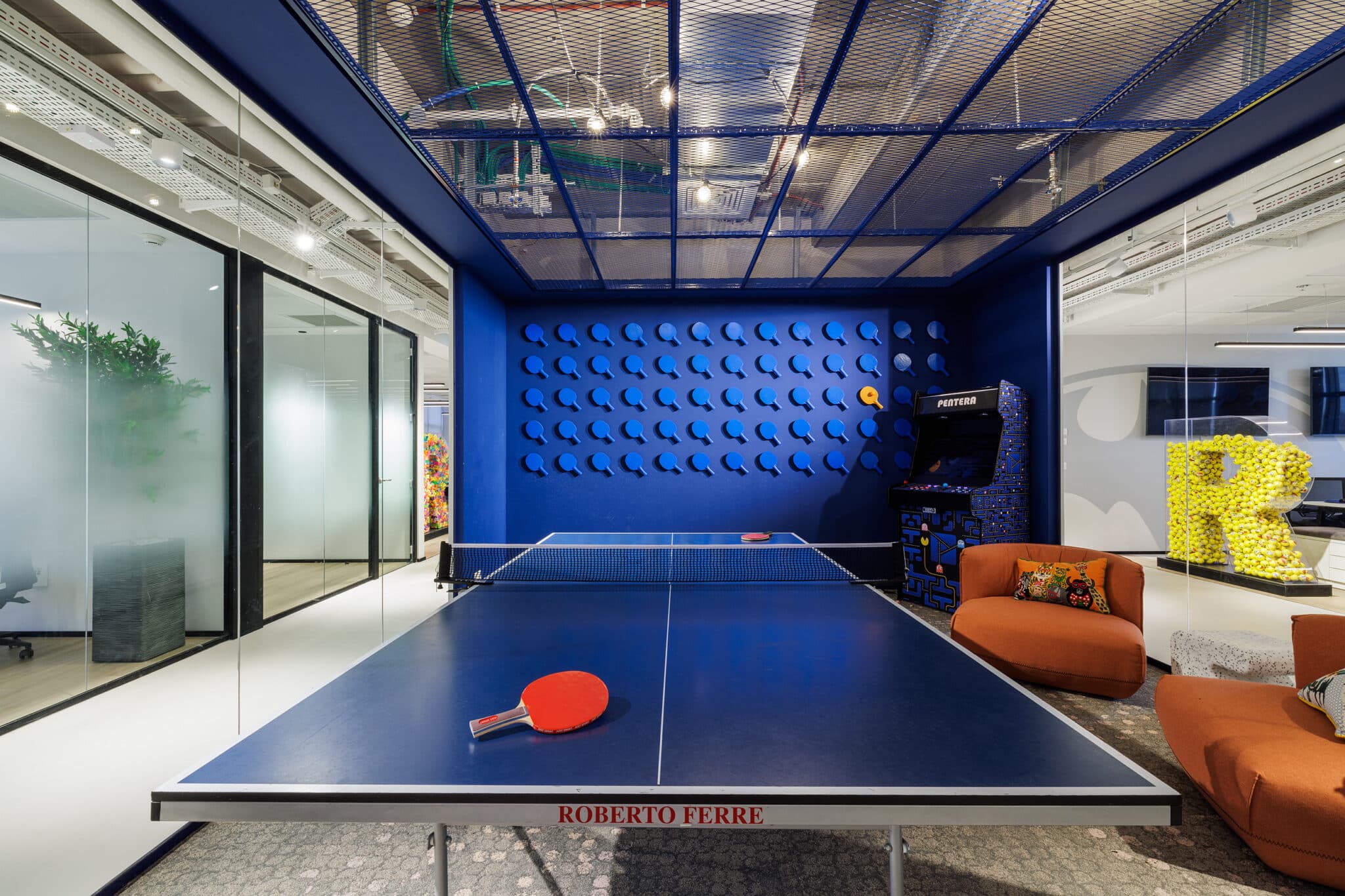 Blue wall of 3D discs and a yellow 3D letter in a games room