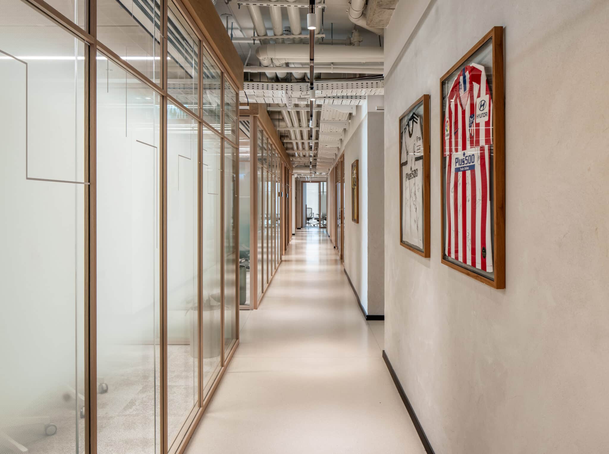 Framed football shirts opposite frosted glass office partitions