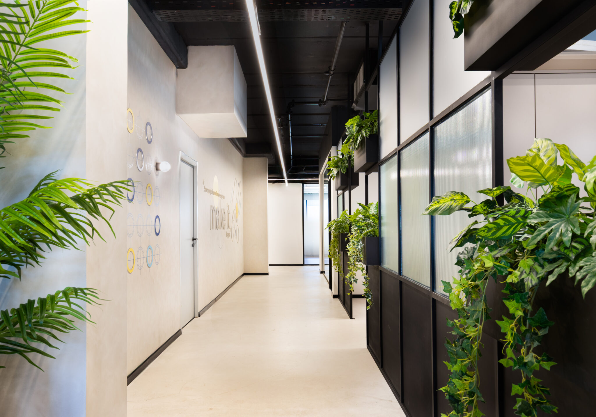 Ring graphics and a logo on the corridor wall beside planters
