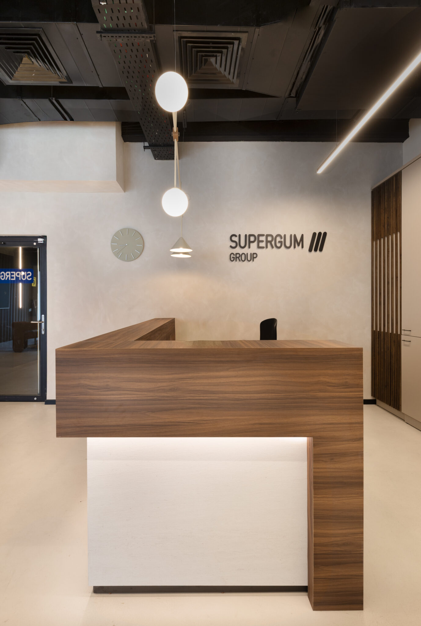 SUPERGUM GROUP logo on the reception wall above a wood desk