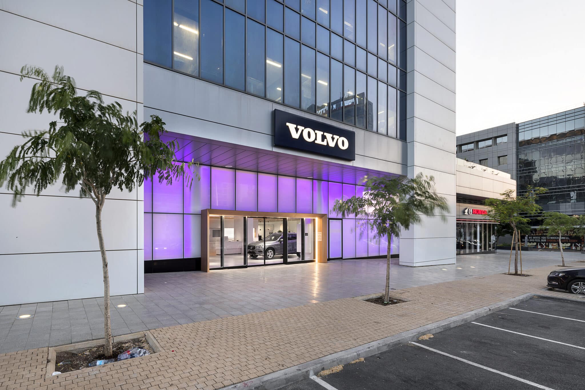 VOLVO sign above a backlit purple facade at dusk