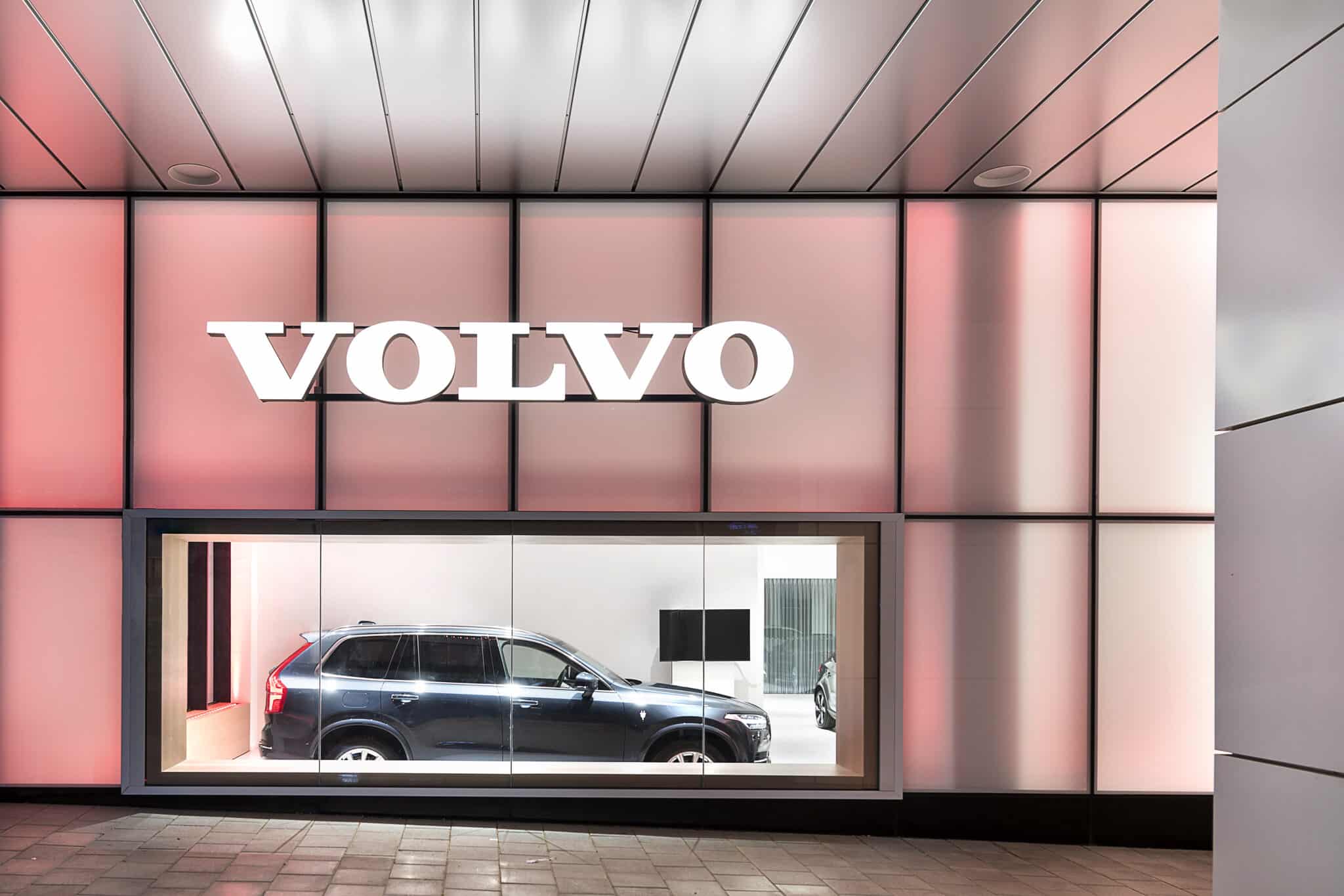 Dimensional VOLVO letters on a backlit pink facade at night