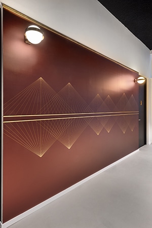 Gold line graphic in a triangular pattern on a burgundy corridor wall