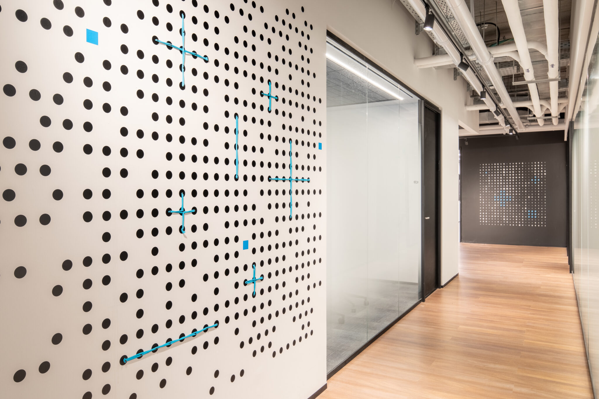 Black dot pattern wall graphic with blue accents in a corridor