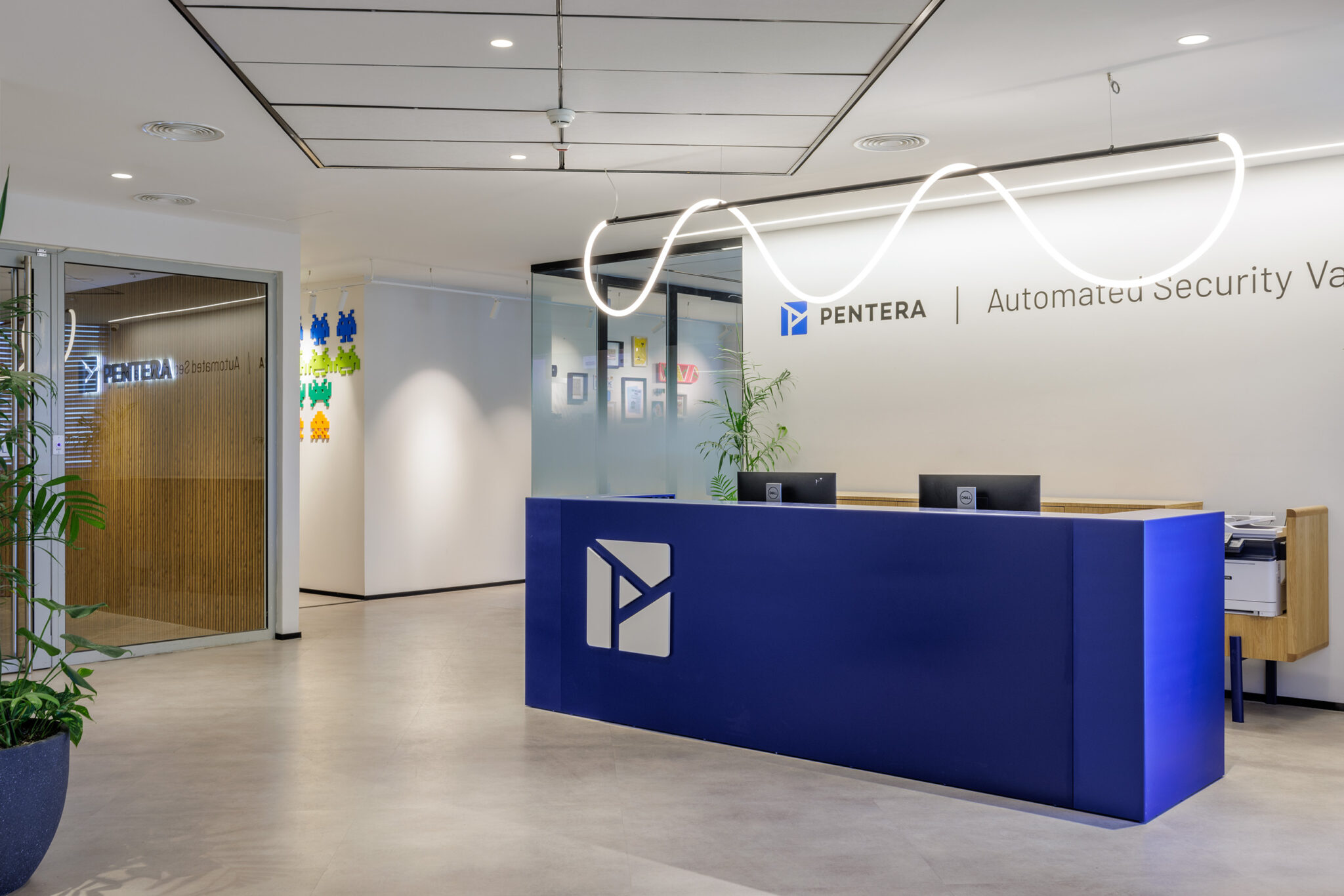 PENTERA logo wall and blue reception desk under a wavy neon line