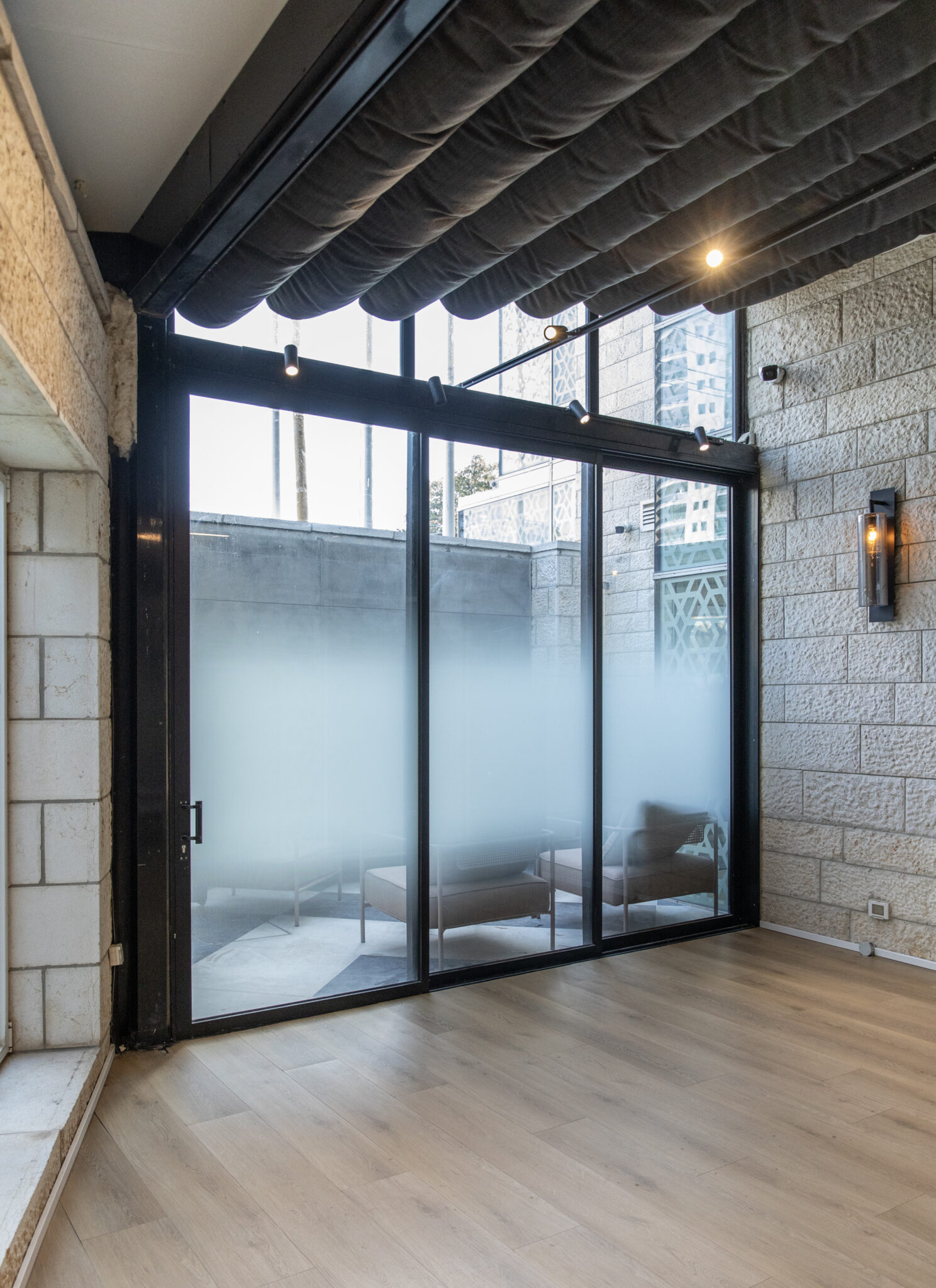 Frosted gradient glass doors opening onto a stone walled terrace