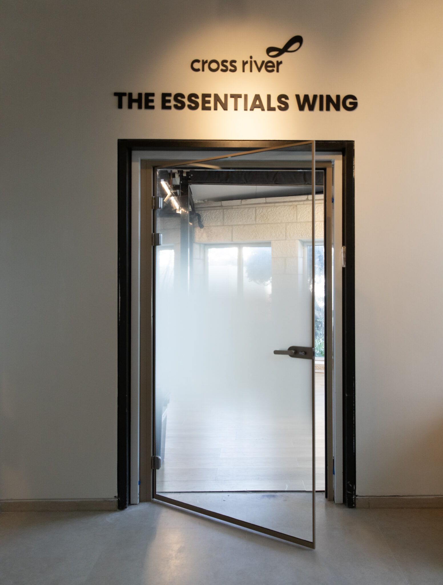 cross river THE ESSENTIALS WING 3D letters above a frosted glass door