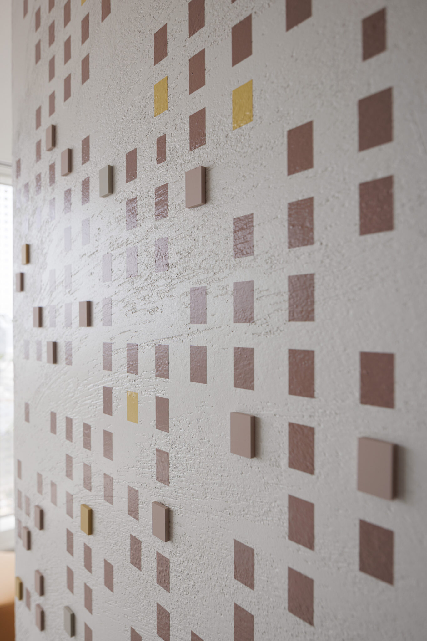 Close-up of 3D pink and gold squares on a textured wall