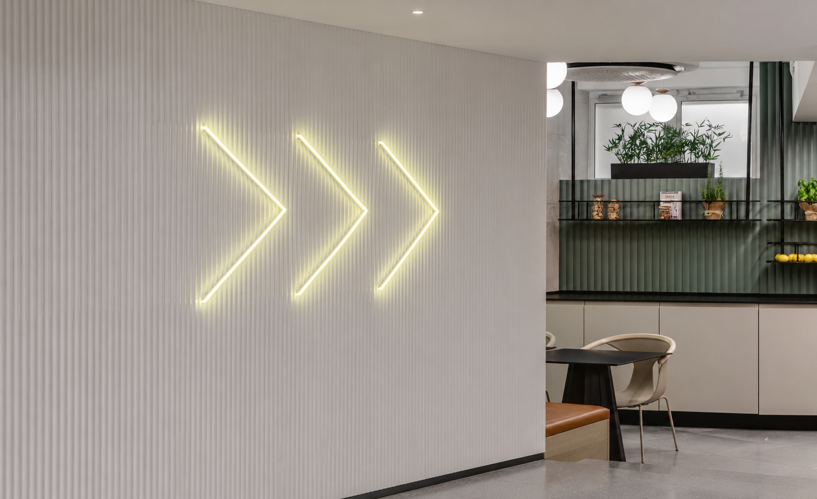 Three white neon chevron arrows on a ribbed wall