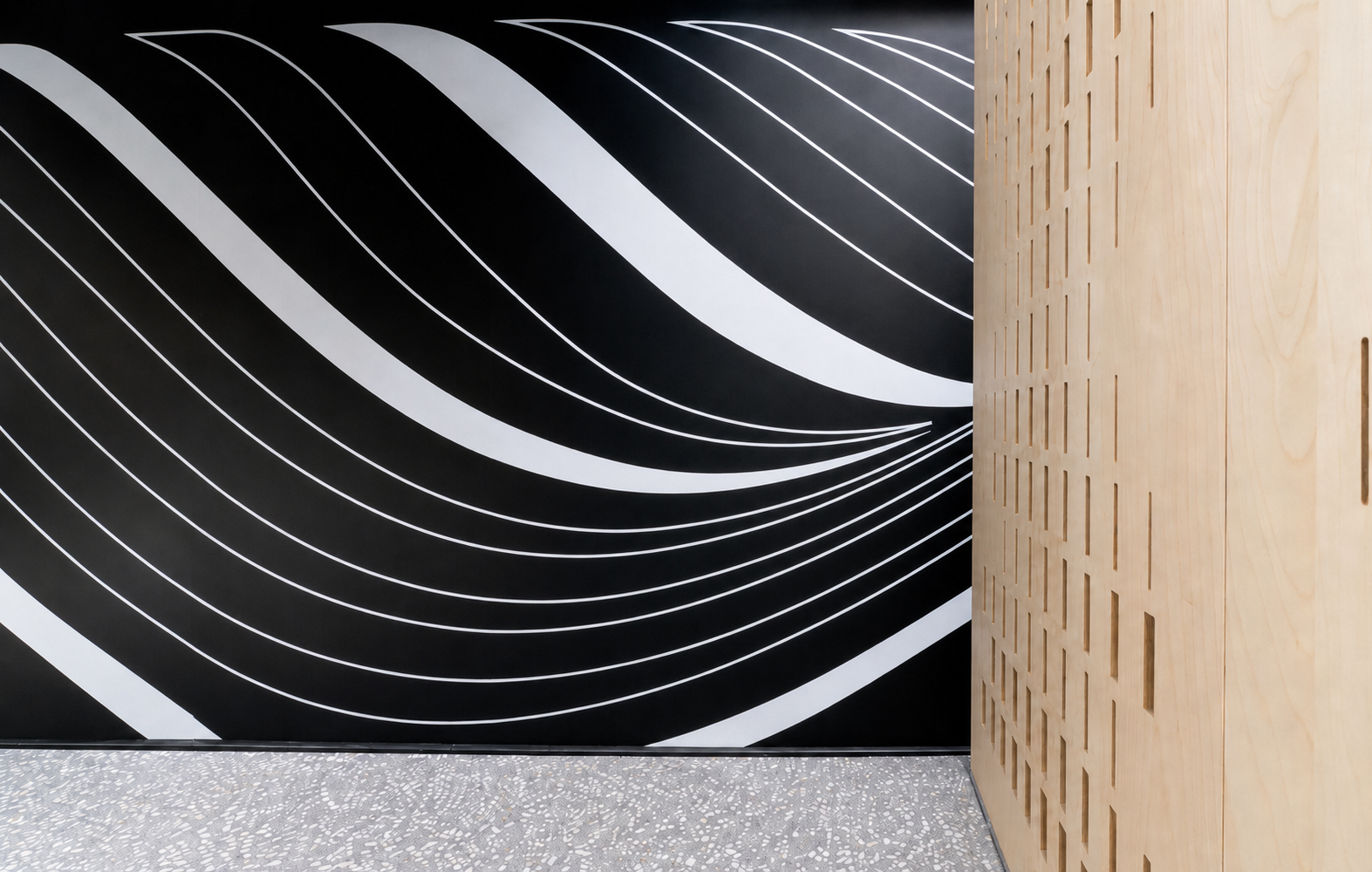 Flowing white ribbon lines on a black wall beside cut wood panels