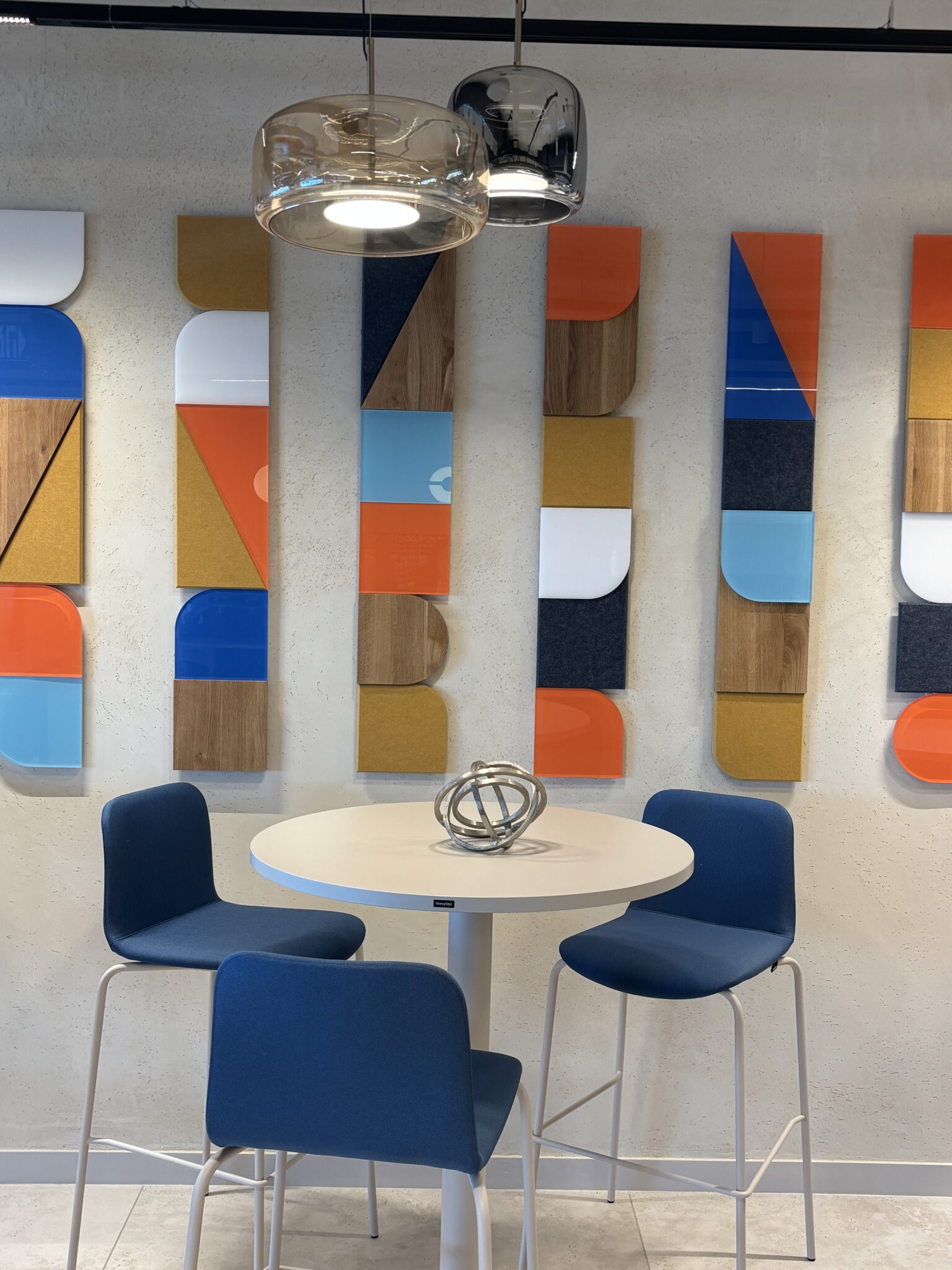 Colourful geometric wall panels behind a round high table