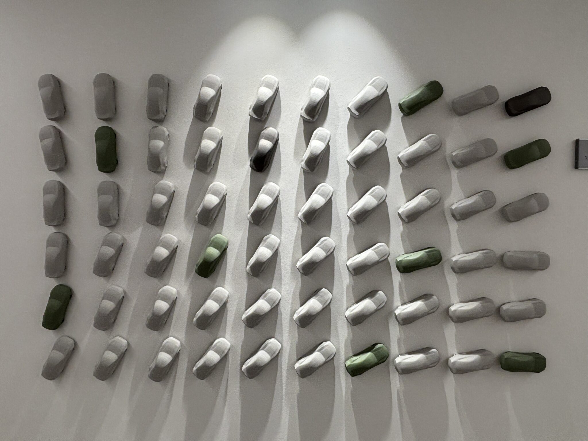 Grid of 3D grey and green sculpted shapes on a wall