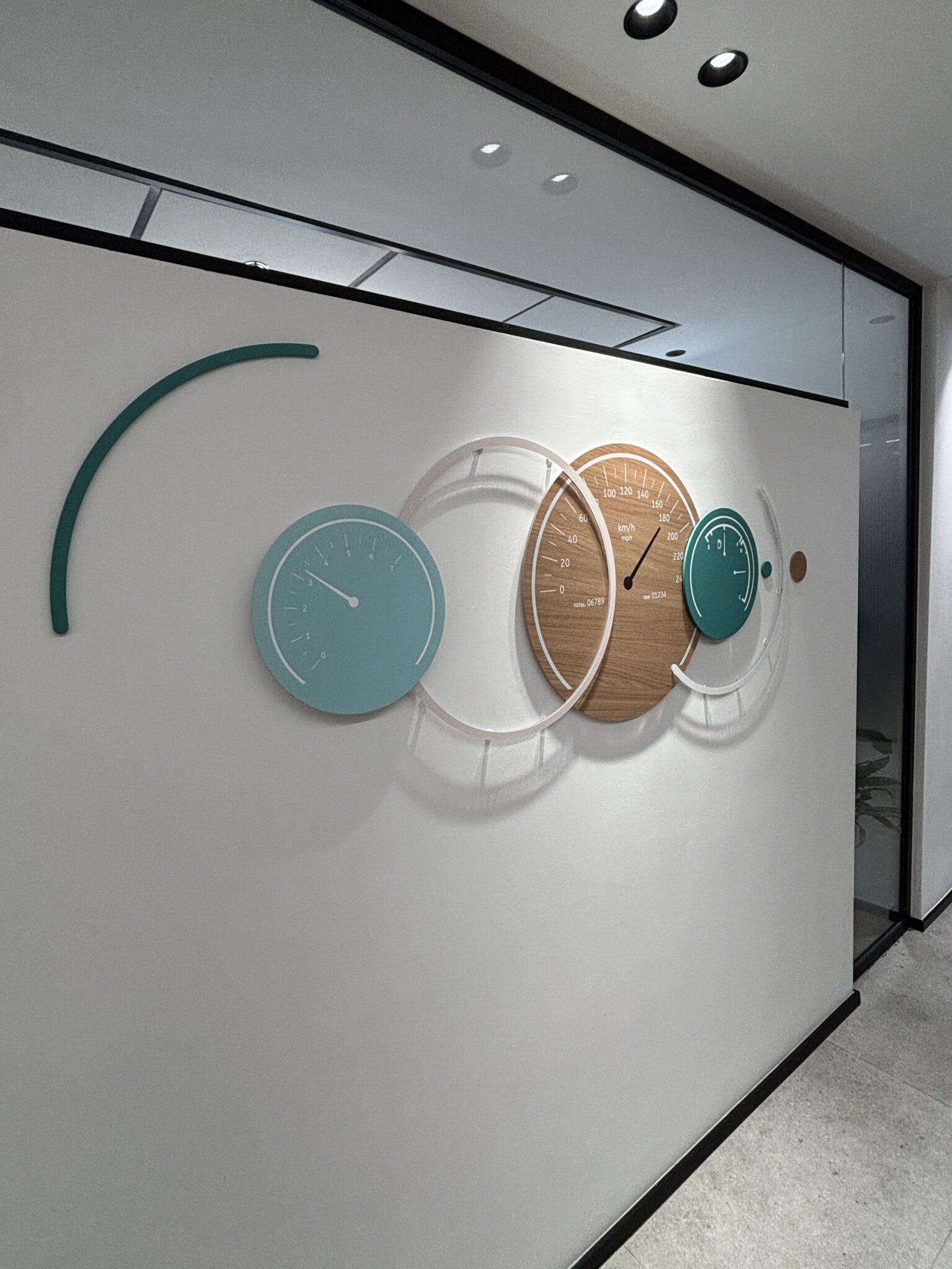 Clock wall installation with layered round wood and teal discs