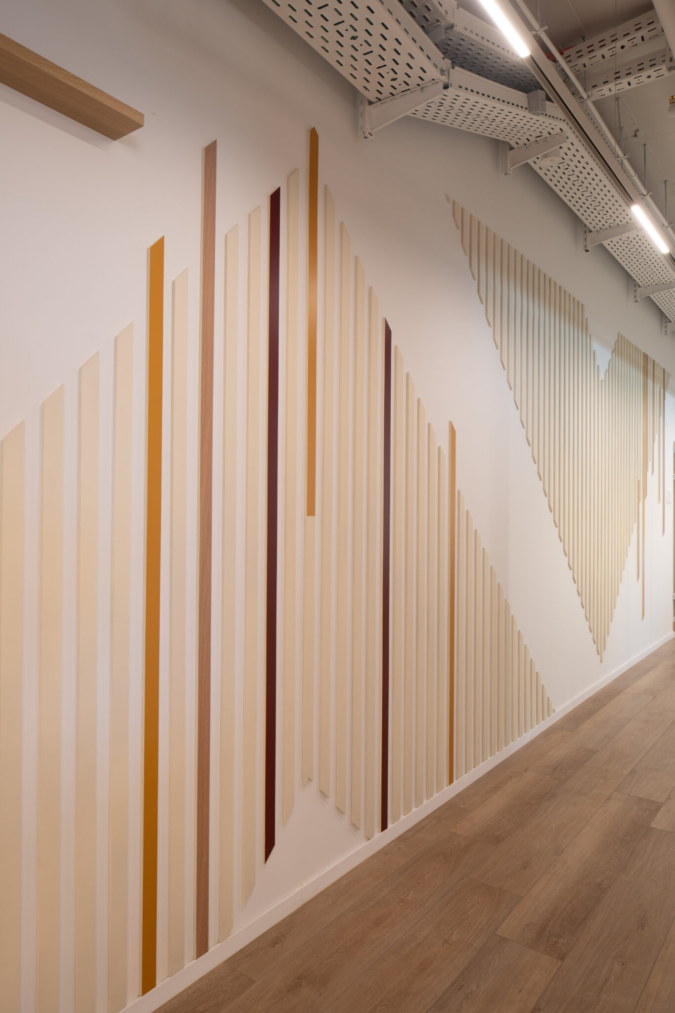 Wood and coloured vertical stripes rising along a corridor wall