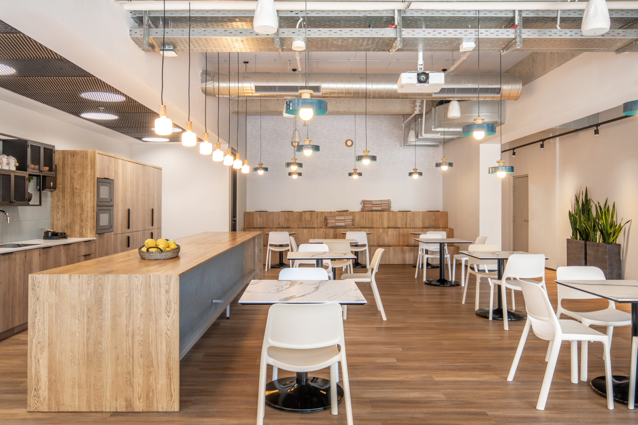 Kitchen with a long wood island and white chairs under pendant lights