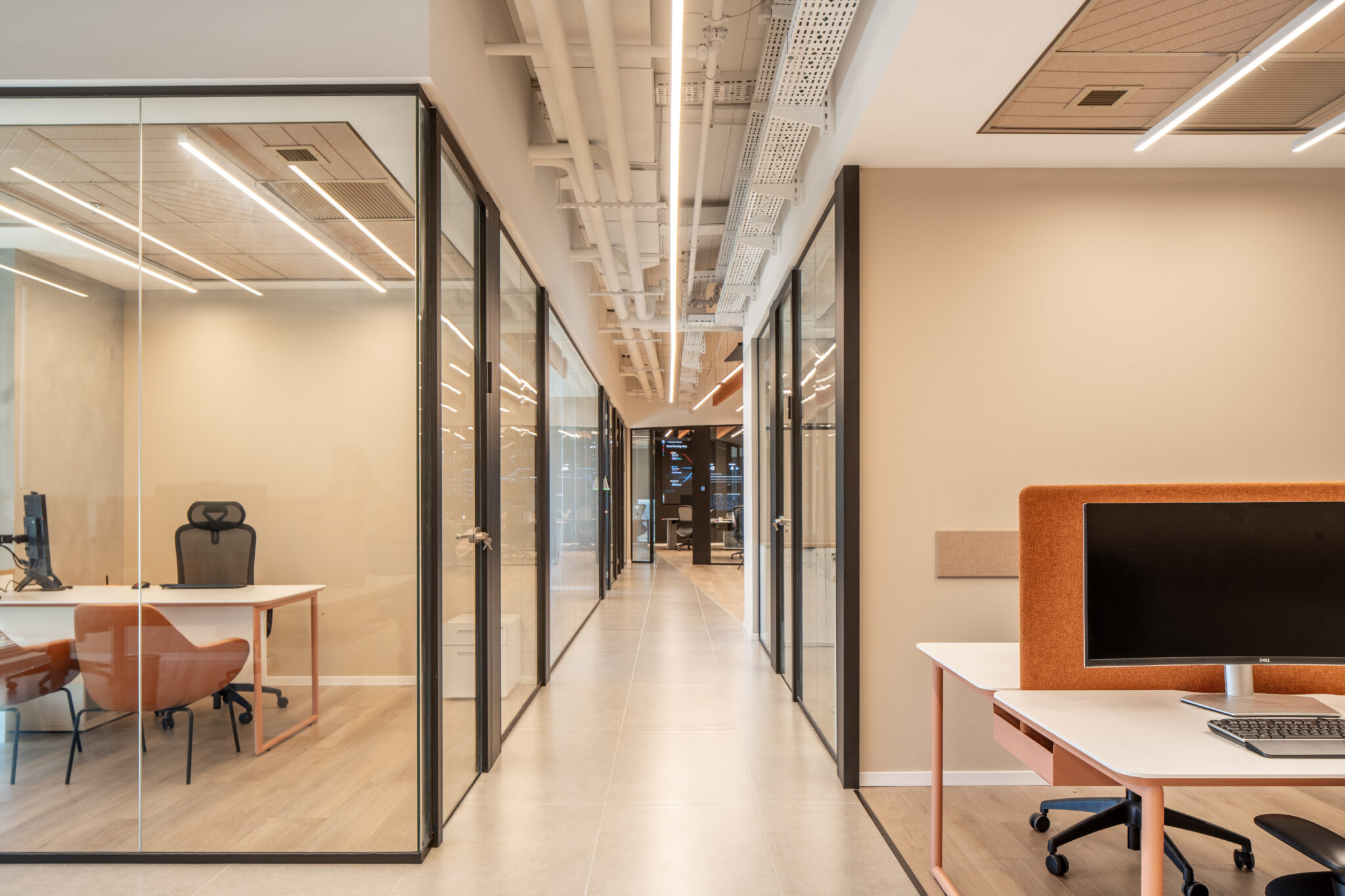 Corridor between glass offices with an orange desk screen