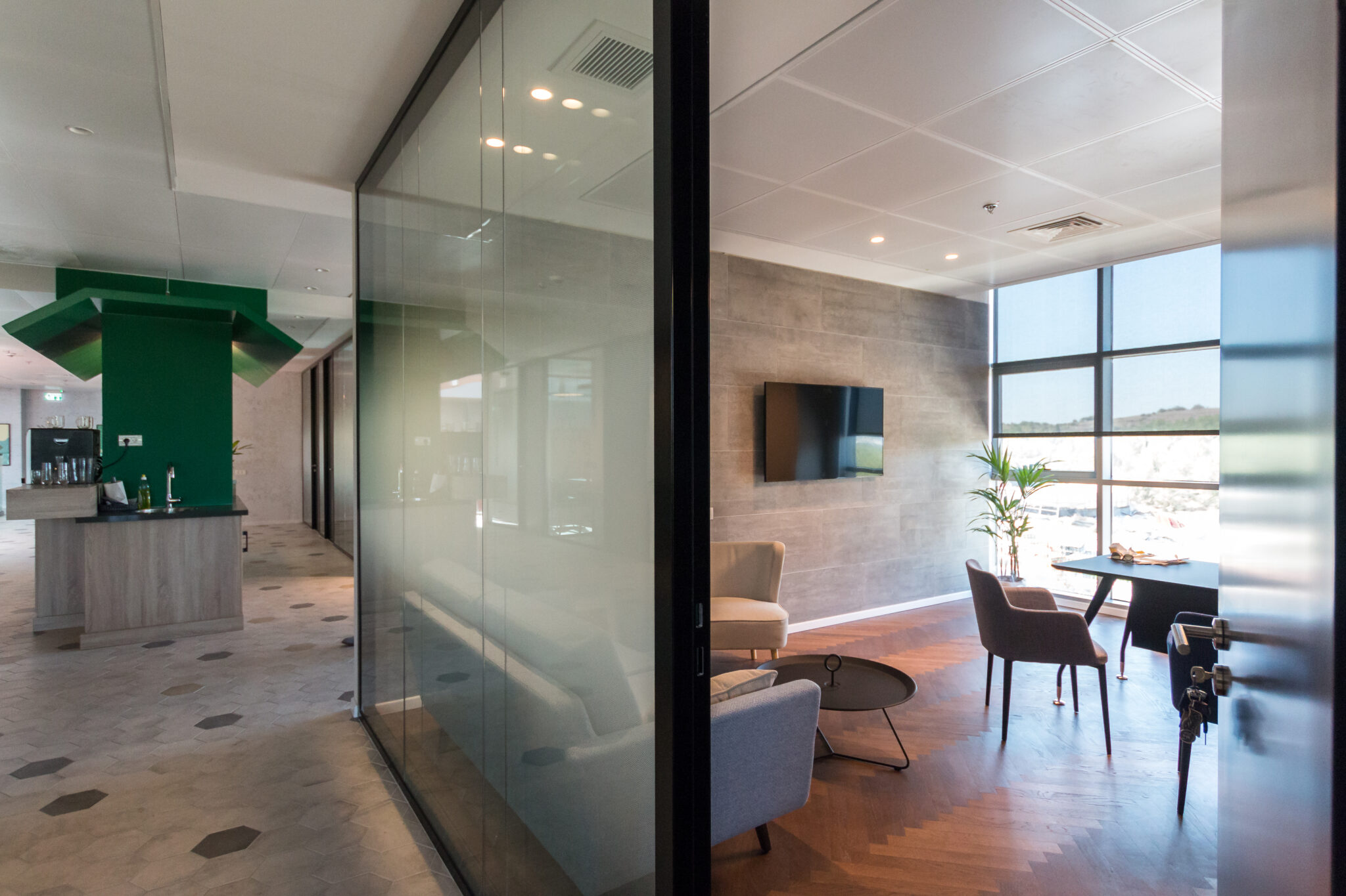 Glass partition between a corridor and a lounge with hex floor tiles