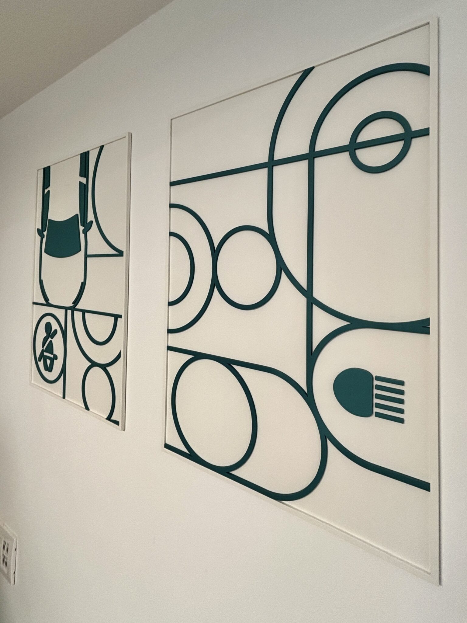 Framed dark green line art prints on a white wall