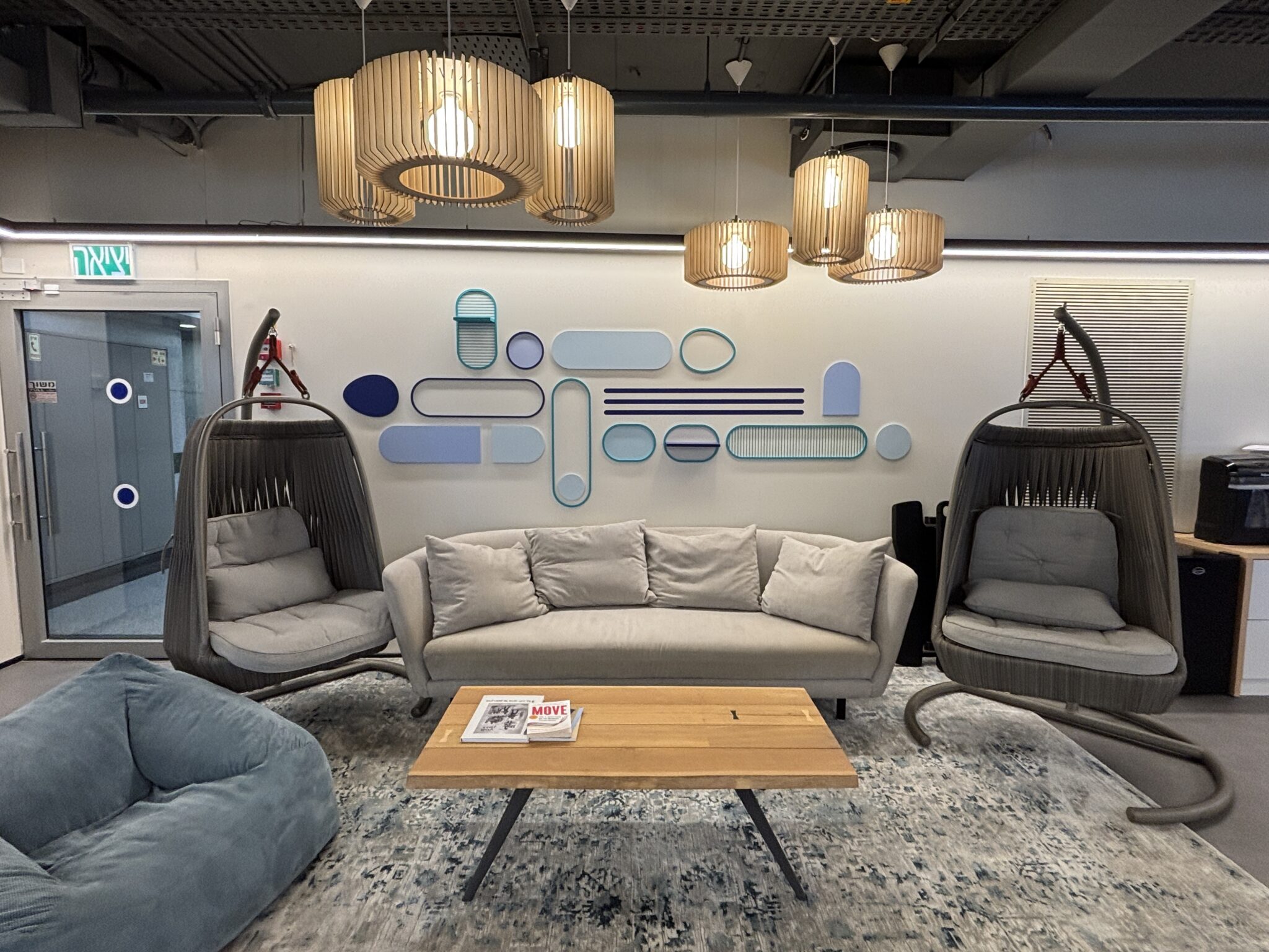 Lounge with hanging chairs, sofa and blue 3D wall shapes
