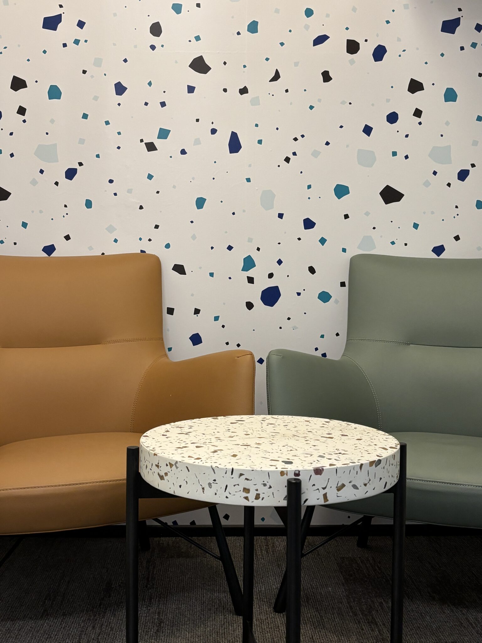 Two armchairs and a terrazzo table by a terrazzo pattern wall