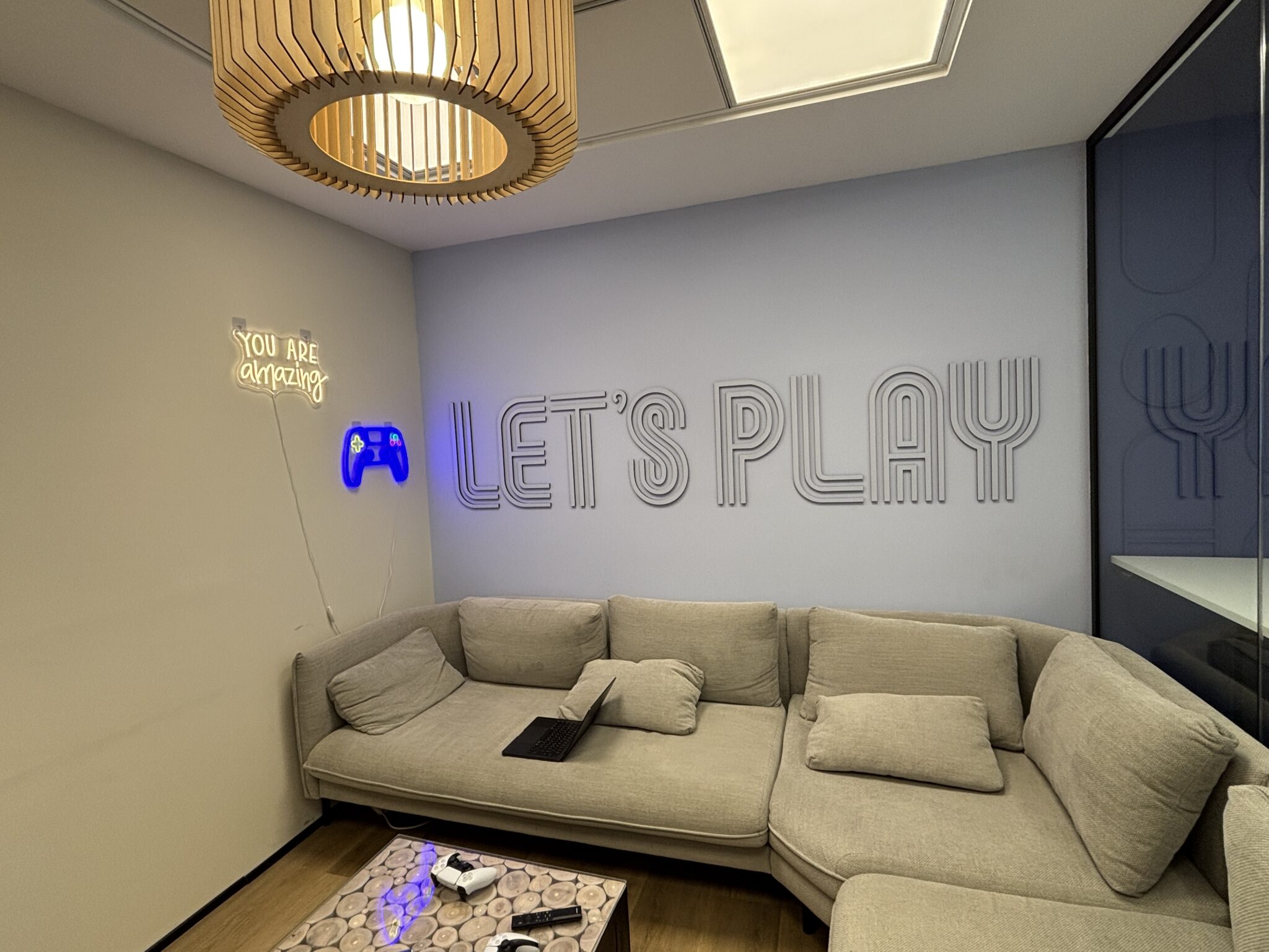 Lounge with grey sofa, neon sign and Let's Play 3D letters
