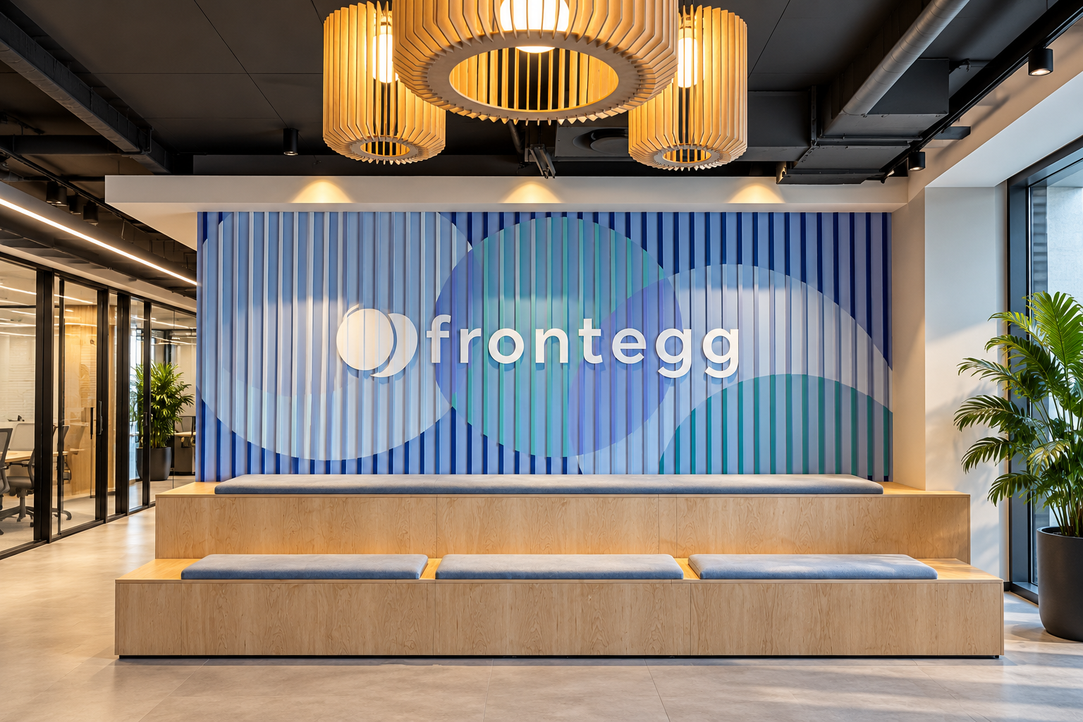 frontegg logo on a blue slat wall above wooden seating
